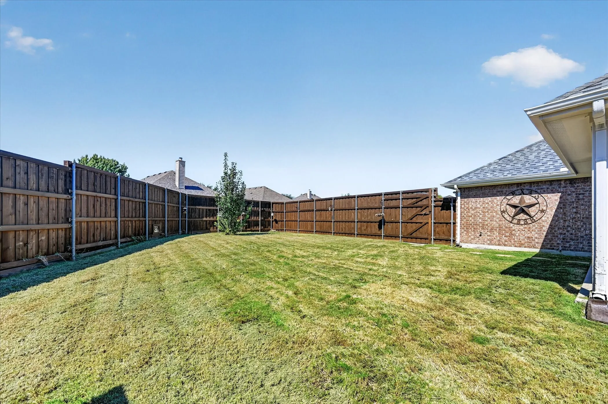 Expansive backyard featuring a wood privacy fence and a small tree