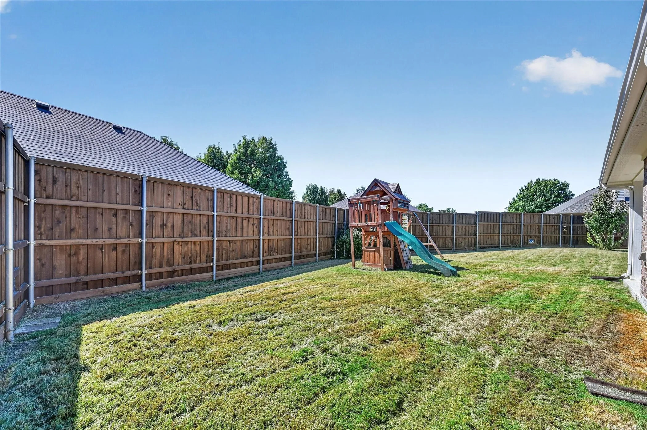 Spacious rear lawn with wood fencing and mature perimeter trees