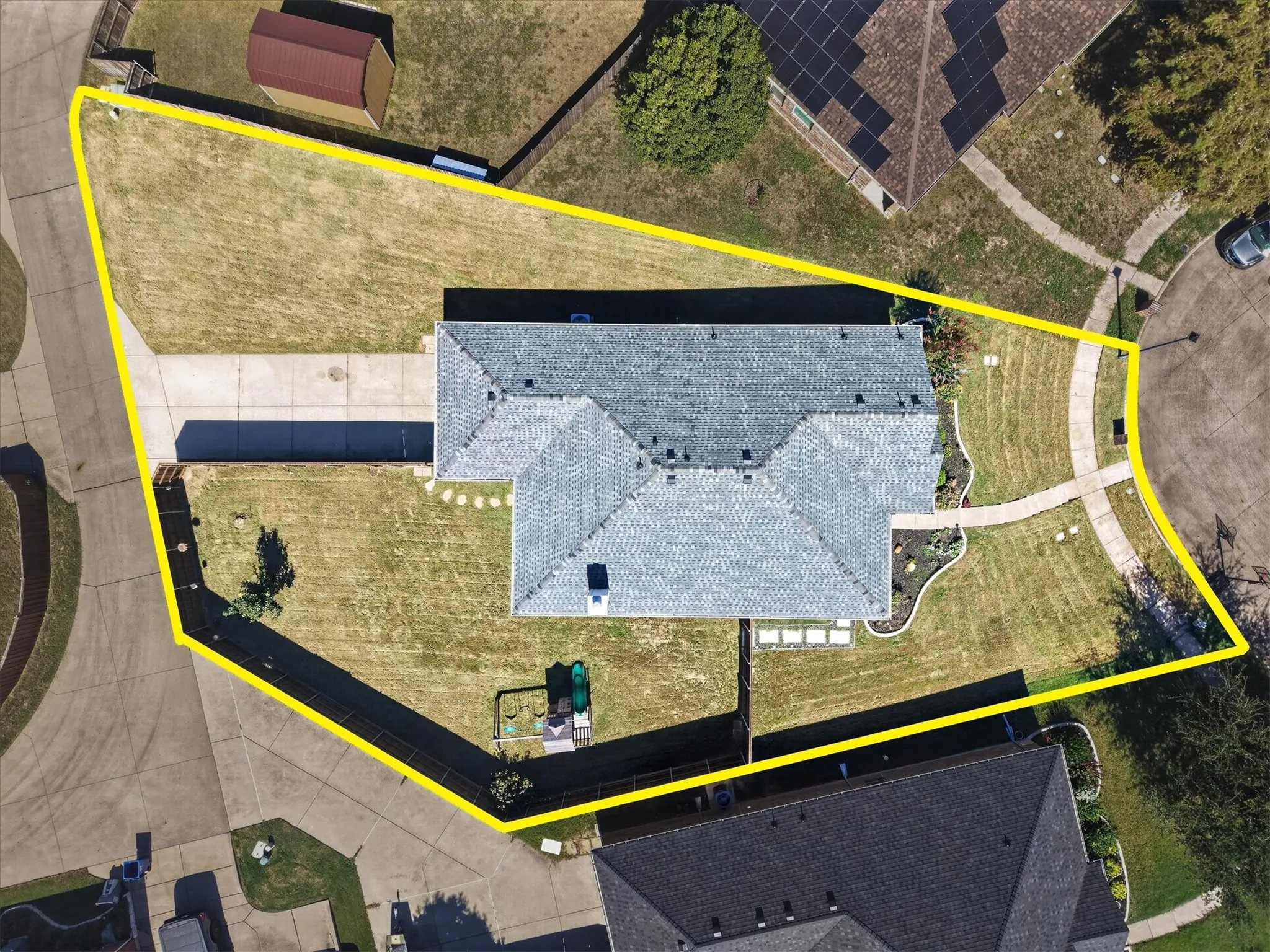 Pitched roof residence featuring a concrete driveway and walkway, bordered by a manicured lawn and landscaping