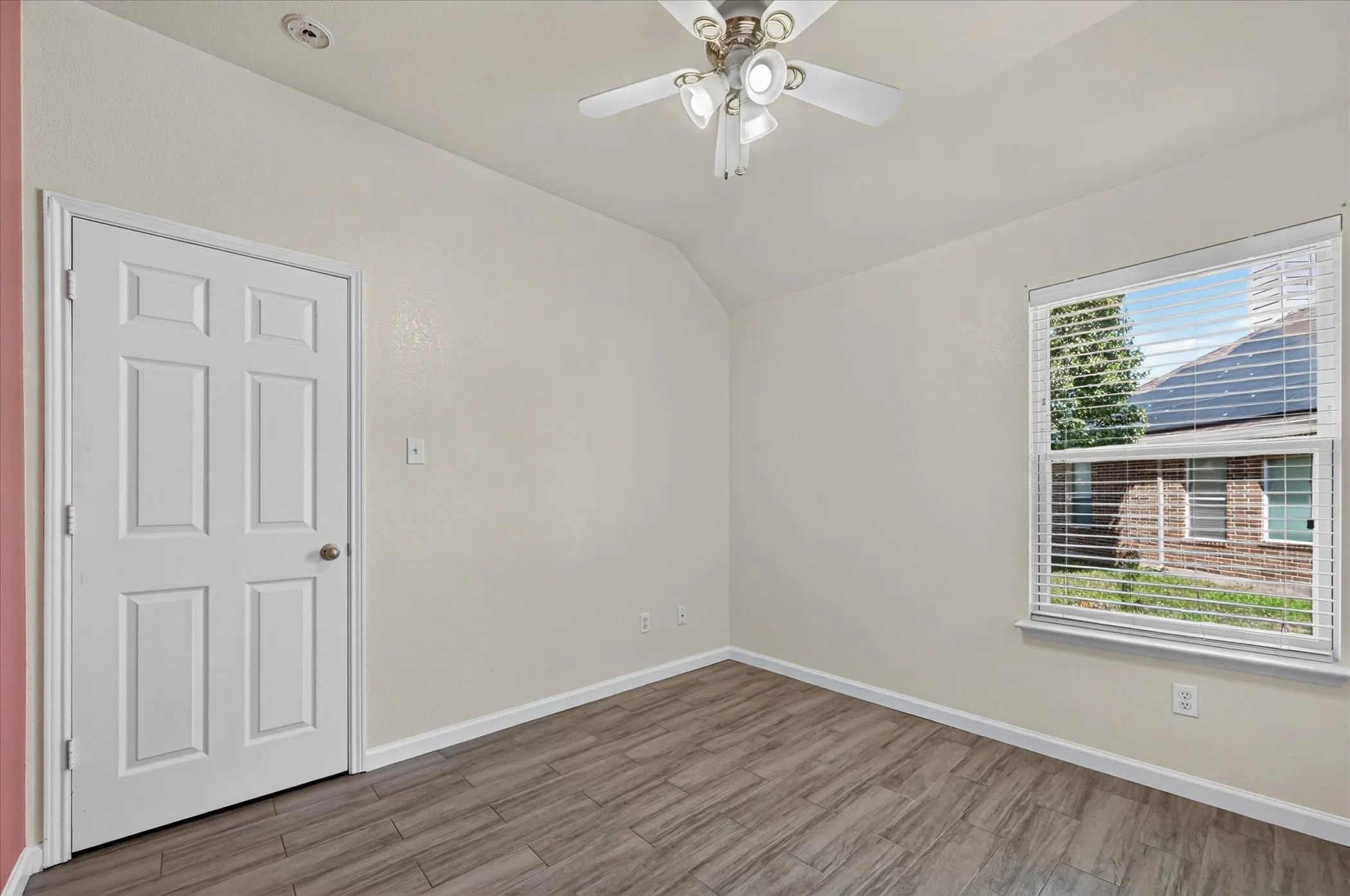 Bright bedroom featuring wood-finish flooring, a ceiling fan with integrated lighting, large double-hung window with natural light, and a six-panel closet door