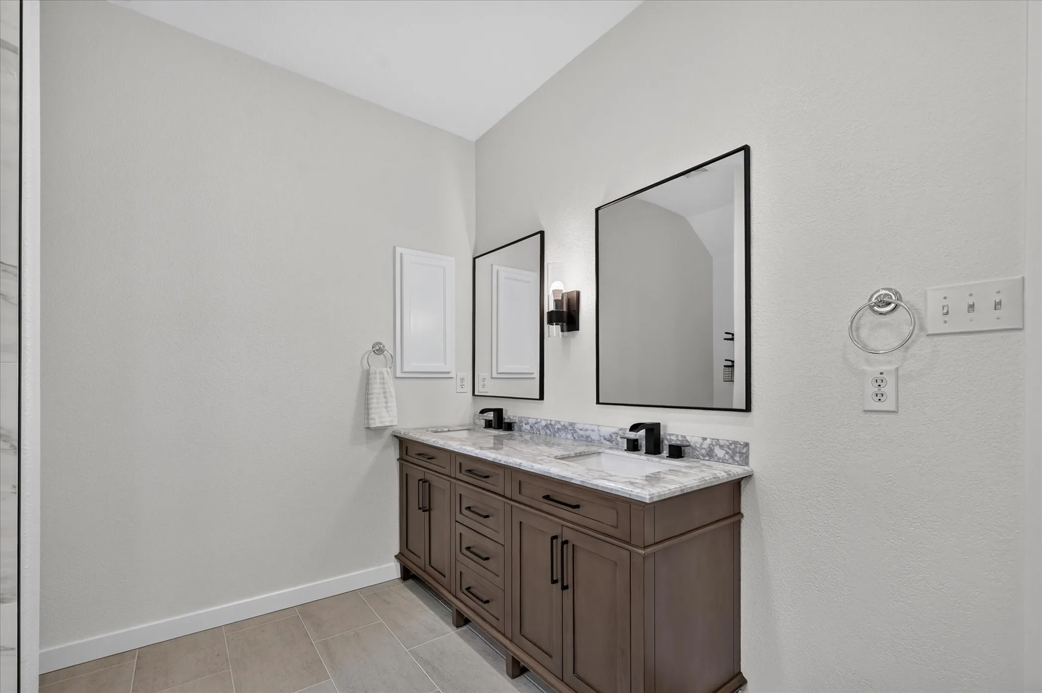 Dual vanity with wood-finish cabinetry, under-mount sinks, and a stone-finish countertop