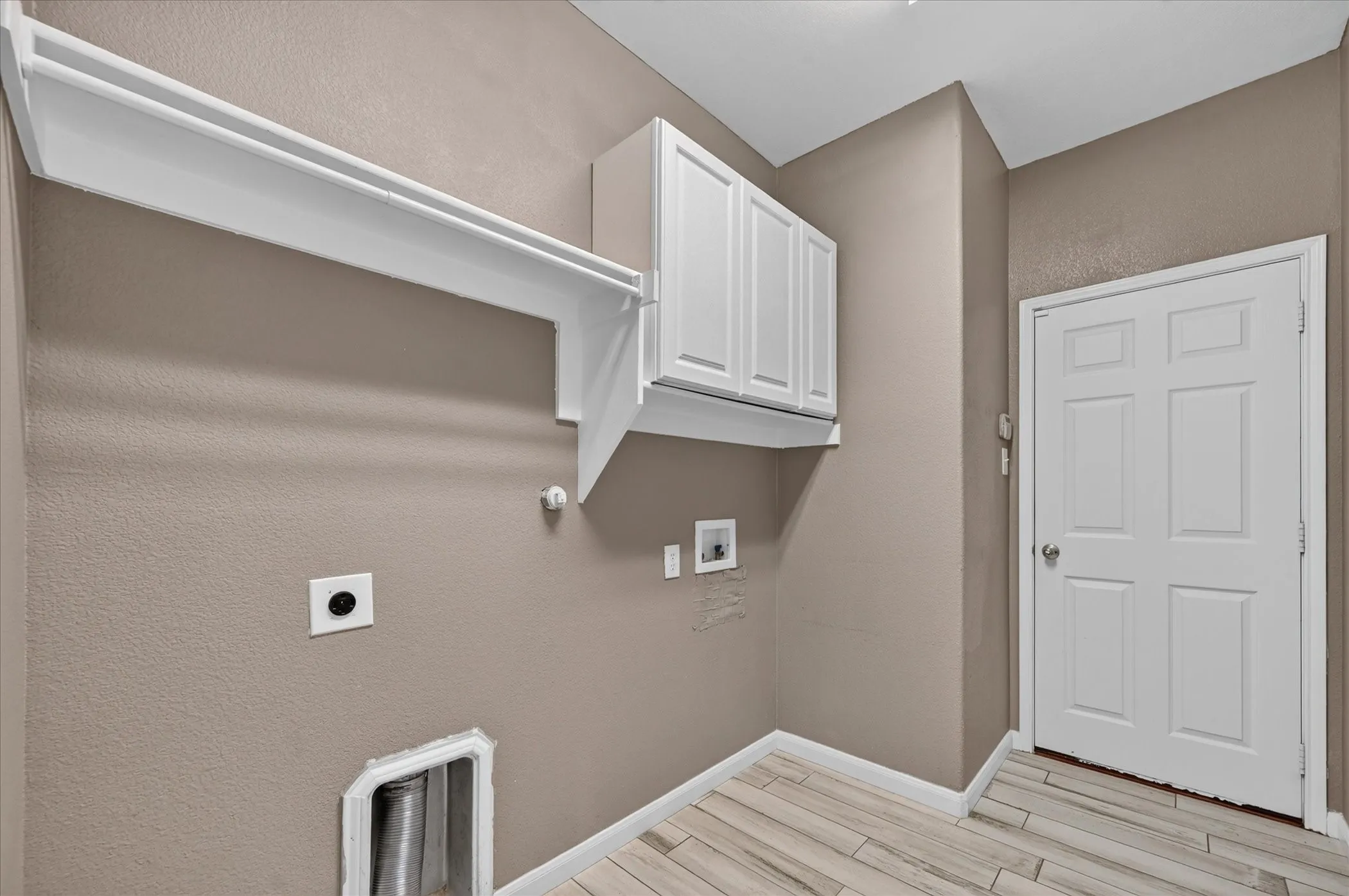 White paneled cabinetry, wood-finish flooring, and white interior door