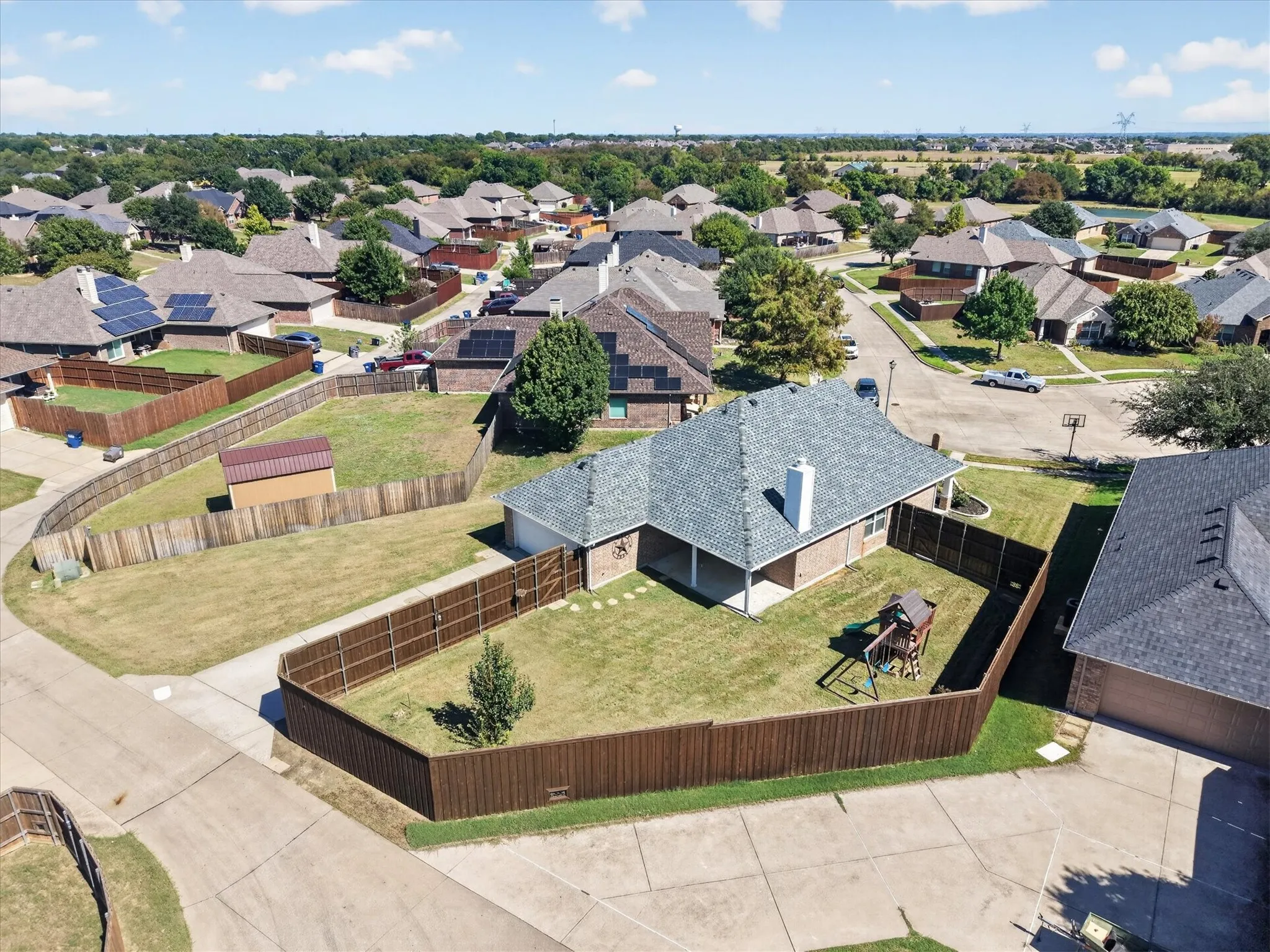 Expansive backyard retreat featuring a manicured lawn, mature landscaping, and wood-finish privacy fencing