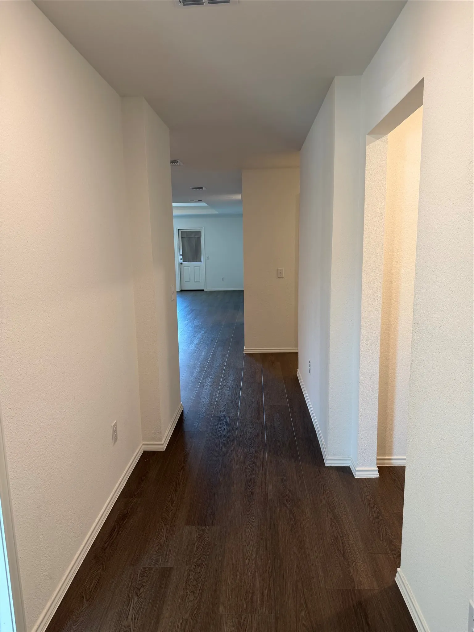 Hallway featuring wood-finish flooring and white painted walls