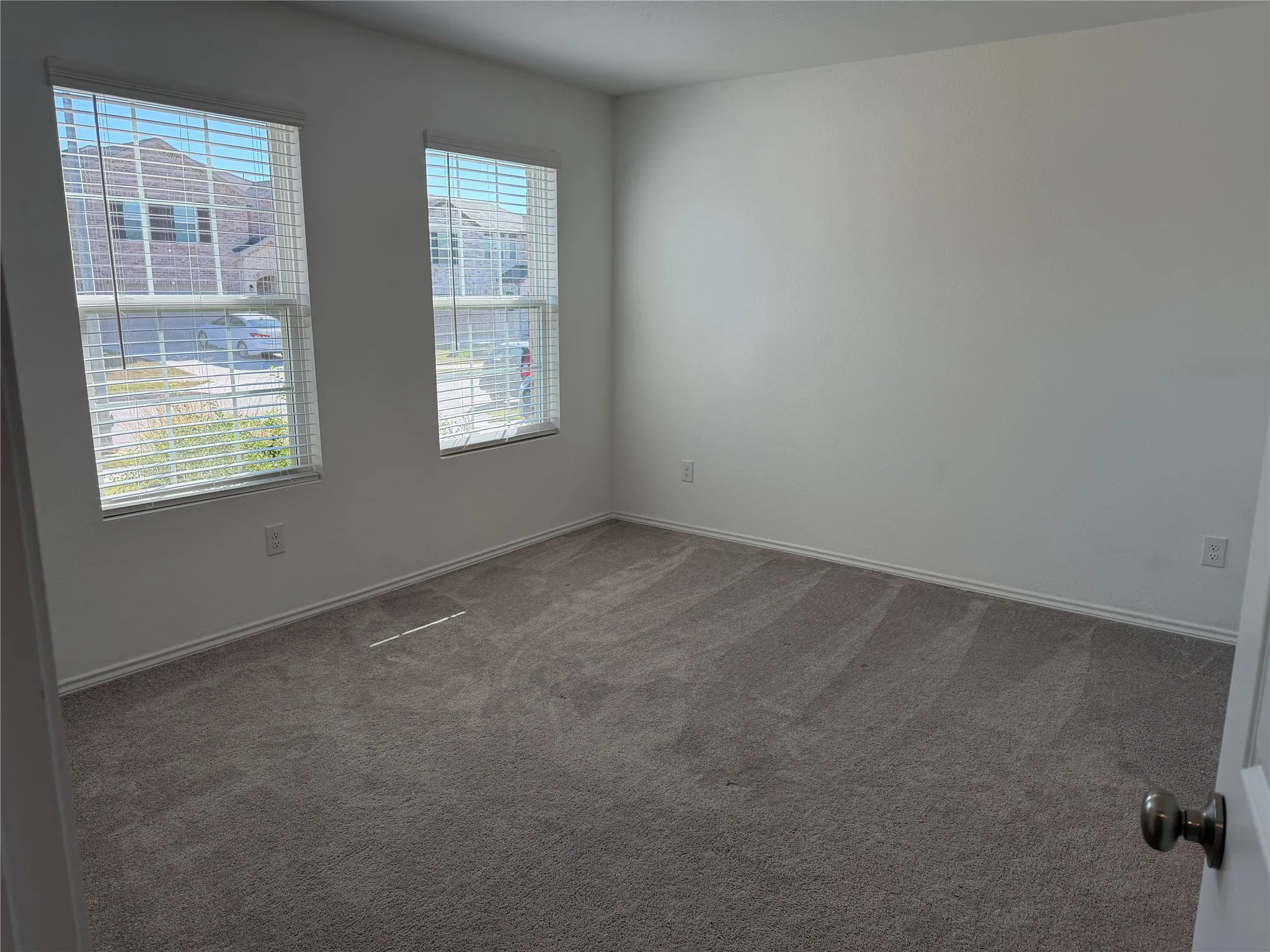 Neutral wall finishes, two windows with blinds, and carpeted flooring