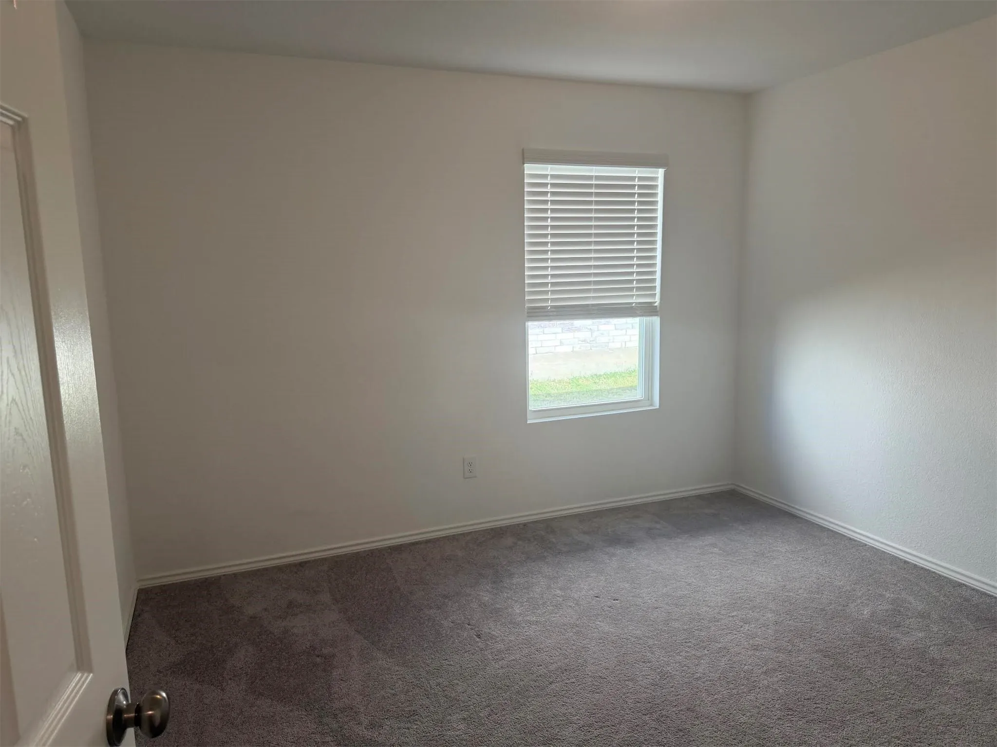 Neutral tone wall finish with a single window featuring horizontal blinds