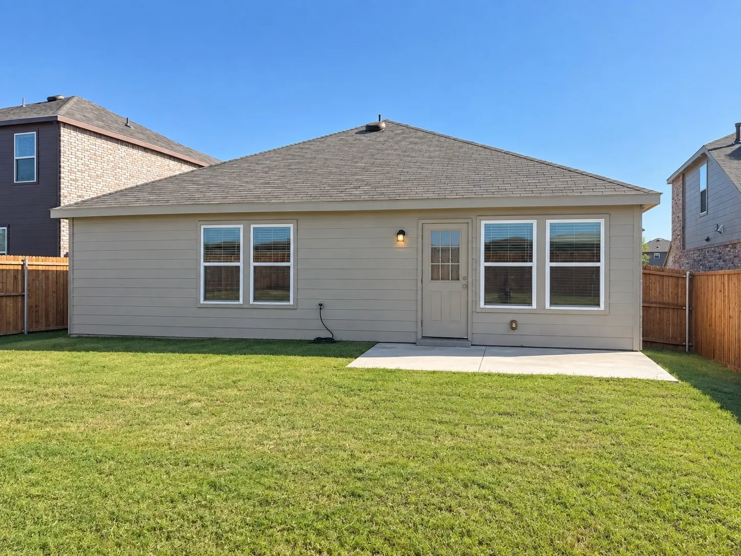 Expansive backyard with a flat lawn, concrete patio, and privacy fencing