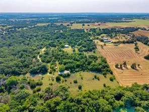 Expansive rural acreage featuring mature tree-lined boundaries, pastoral open fields, and a winding waterway