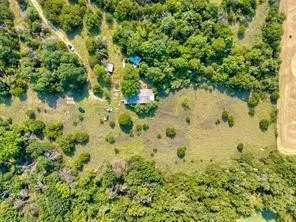 Wooded acreage featuring a single-story residence with a light-toned roof, an additional outbuilding, and expansive cleared areas