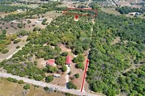 Expansive land parcel featuring multiple structures, mature trees, and direct road frontage
