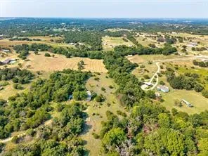 Expansive land offering diverse natural features, including open fields, dense tree coverage, and a winding unpaved road