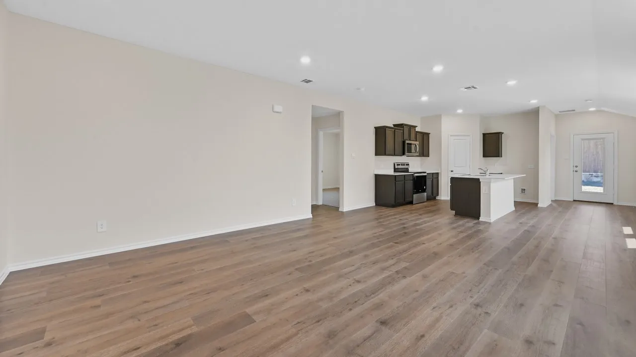 Spacious open-concept living area featuring wood-finish flooring, recessed lighting, and vaulted ceilings