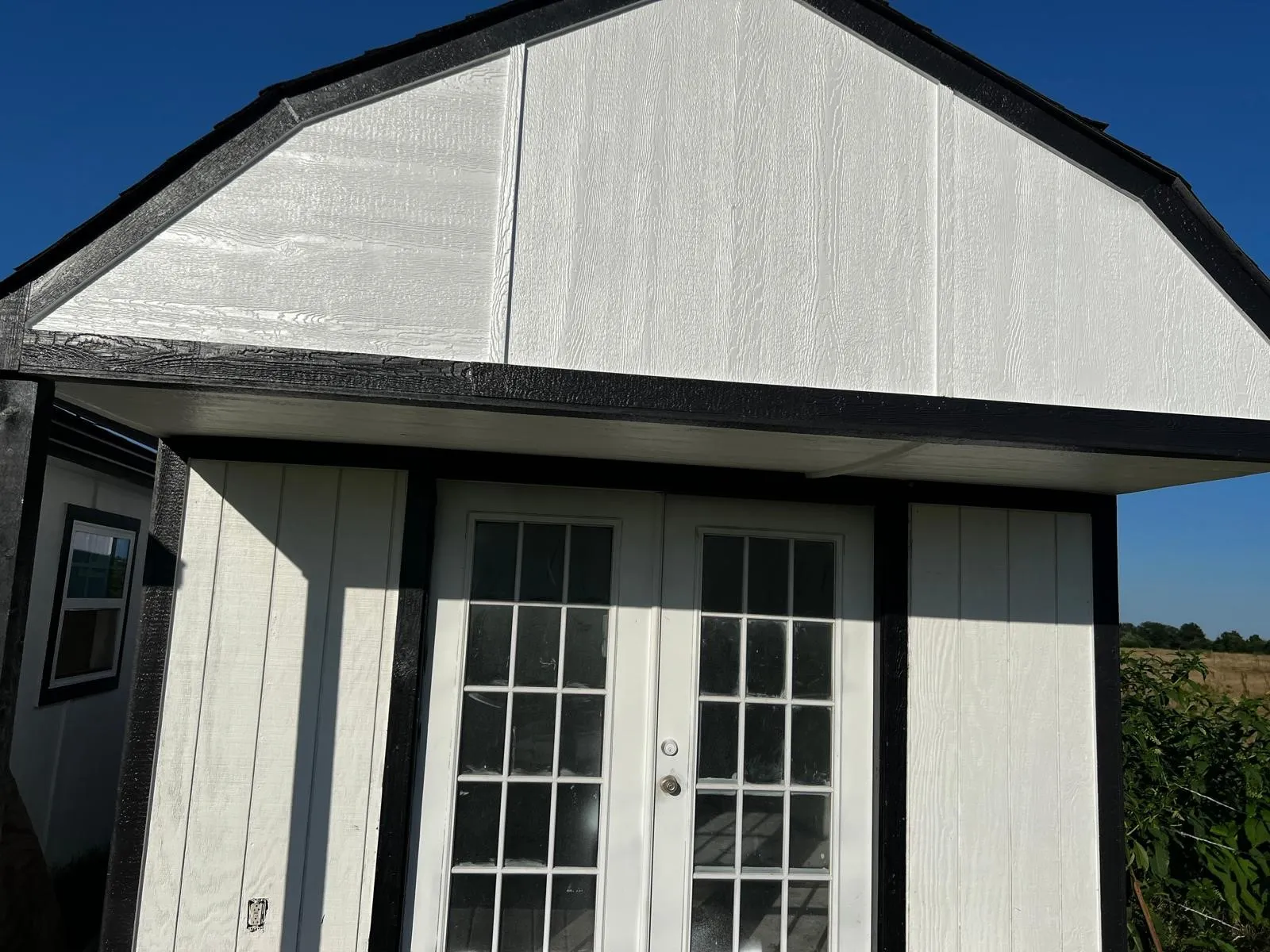 White siding exterior with black trim accents and a gable roof