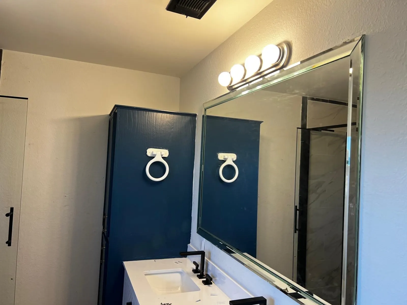 Vanity with integrated sink, matte black faucet, and rectangular mirror with a beveled edge