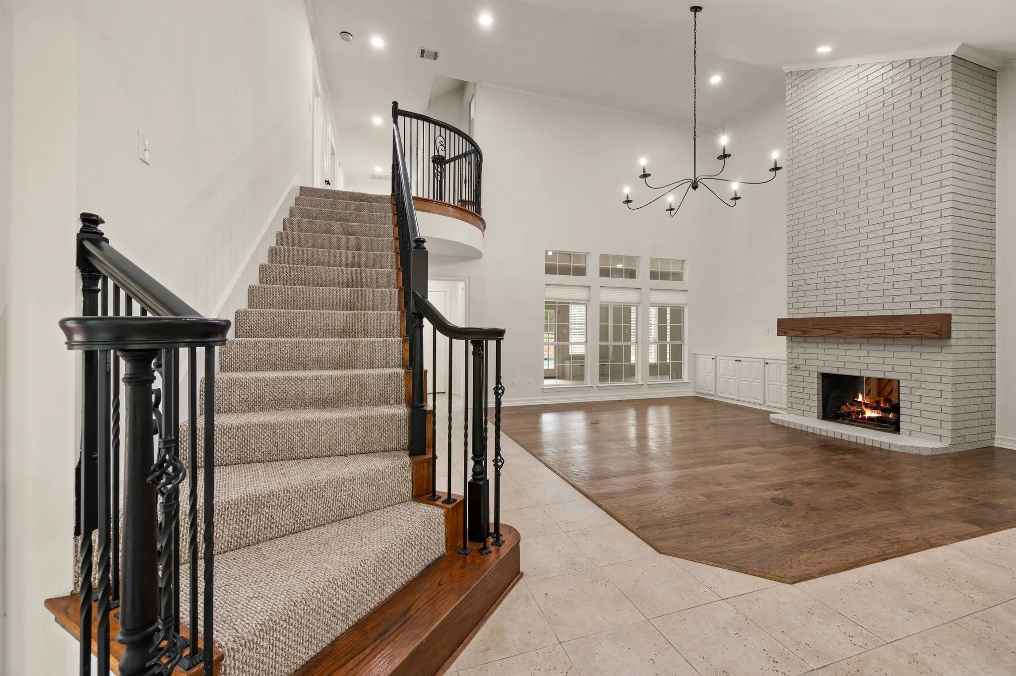 Staircase featuring a towering ceiling, a fireplace, recessed lighting, tile patterned floors, and a notable chandelier