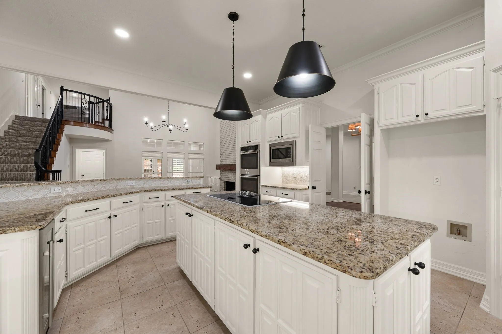 Kitchen featuring an inviting chandelier, appliances with stainless steel finishes, white cabinets, and a kitchen island