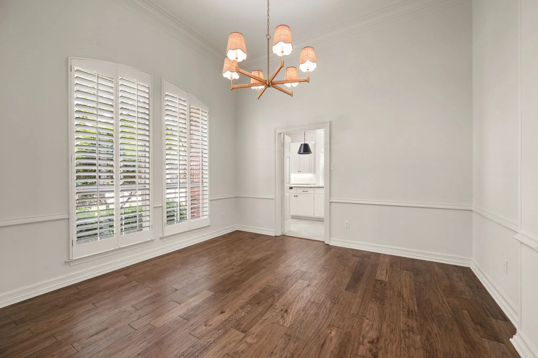 Unfurnished dining area featuring baseboards, a notable chandelier, ornamental molding, and wood finished floors