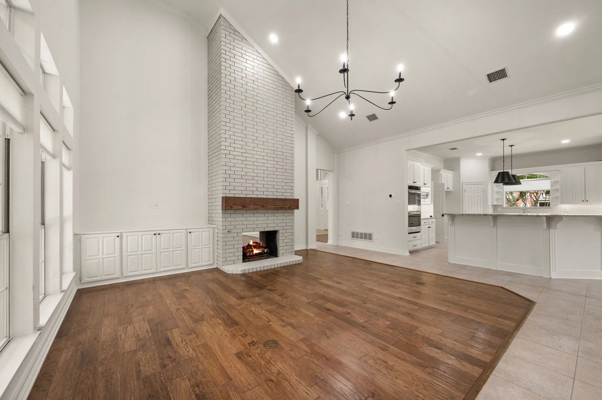 Unfurnished living room with crown molding, high vaulted ceiling, an inviting chandelier, and visible vents