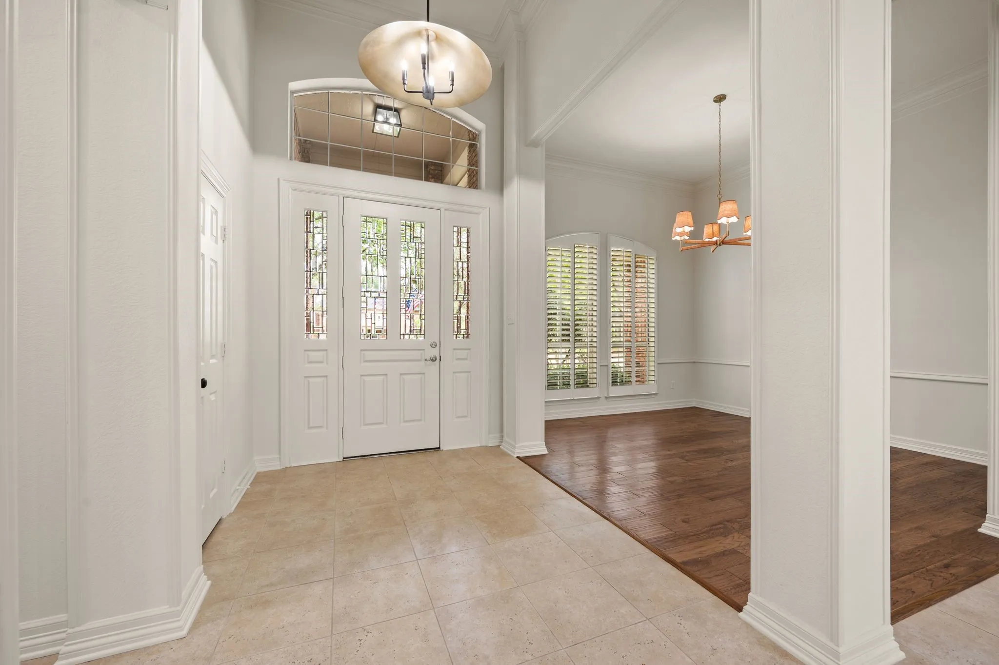 Tiled entryway featuring an inviting chandelier, baseboards, and crown molding
