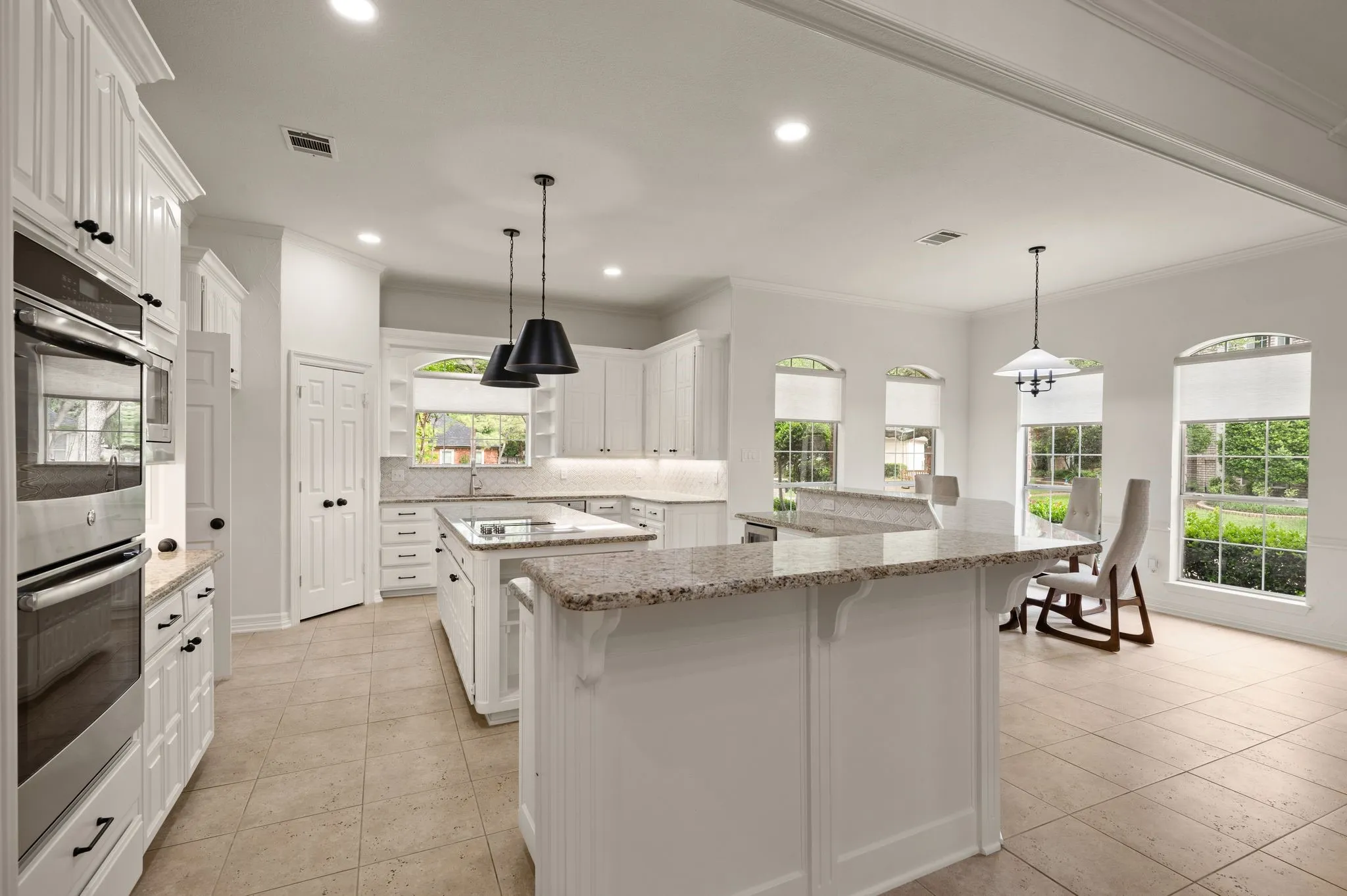 Kitchen with decorative backsplash, a spacious island, a sink, double oven, and ornamental molding