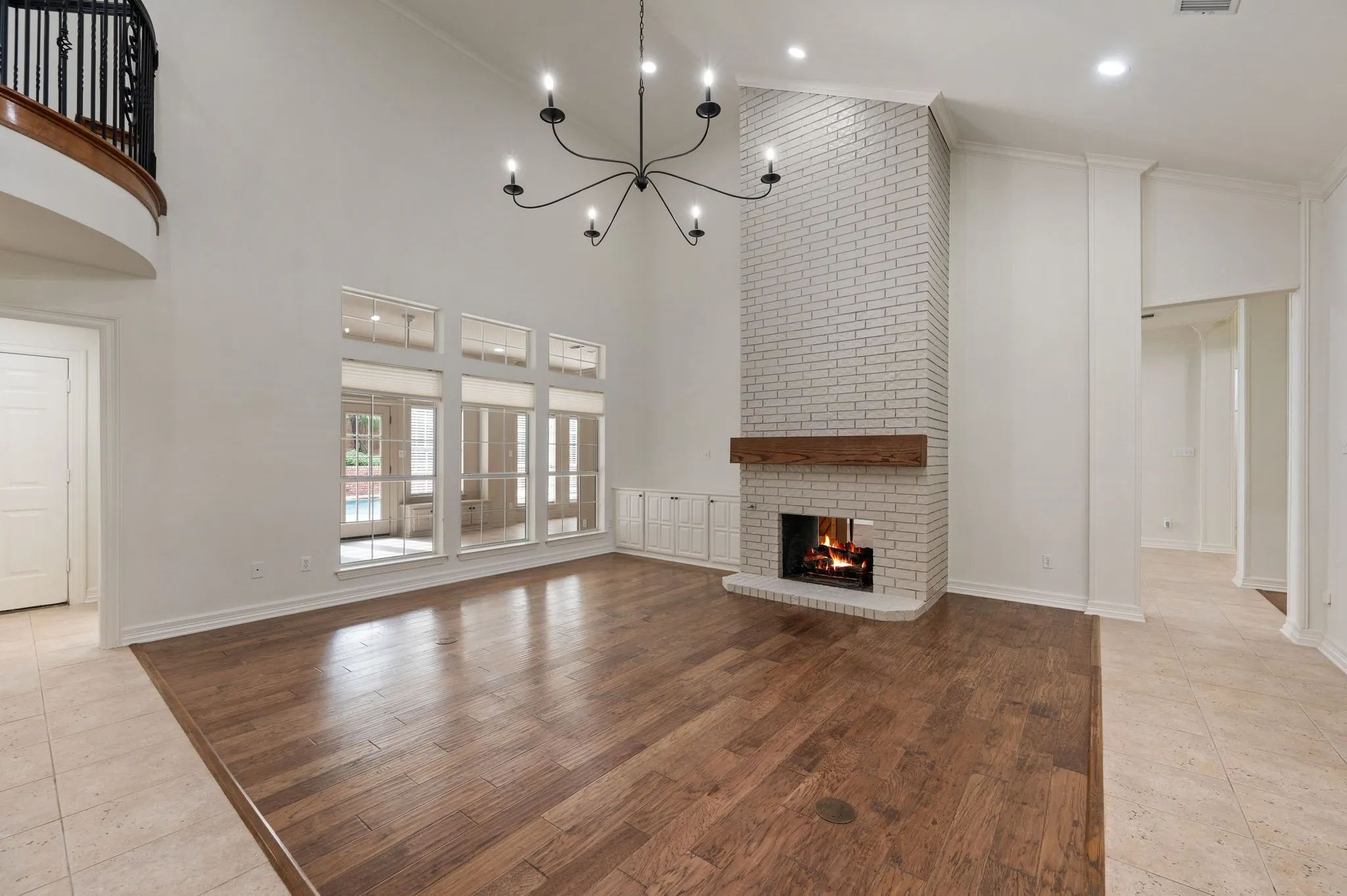 Unfurnished living room with crown molding, a fireplace, high vaulted ceiling, baseboards, and a chandelier