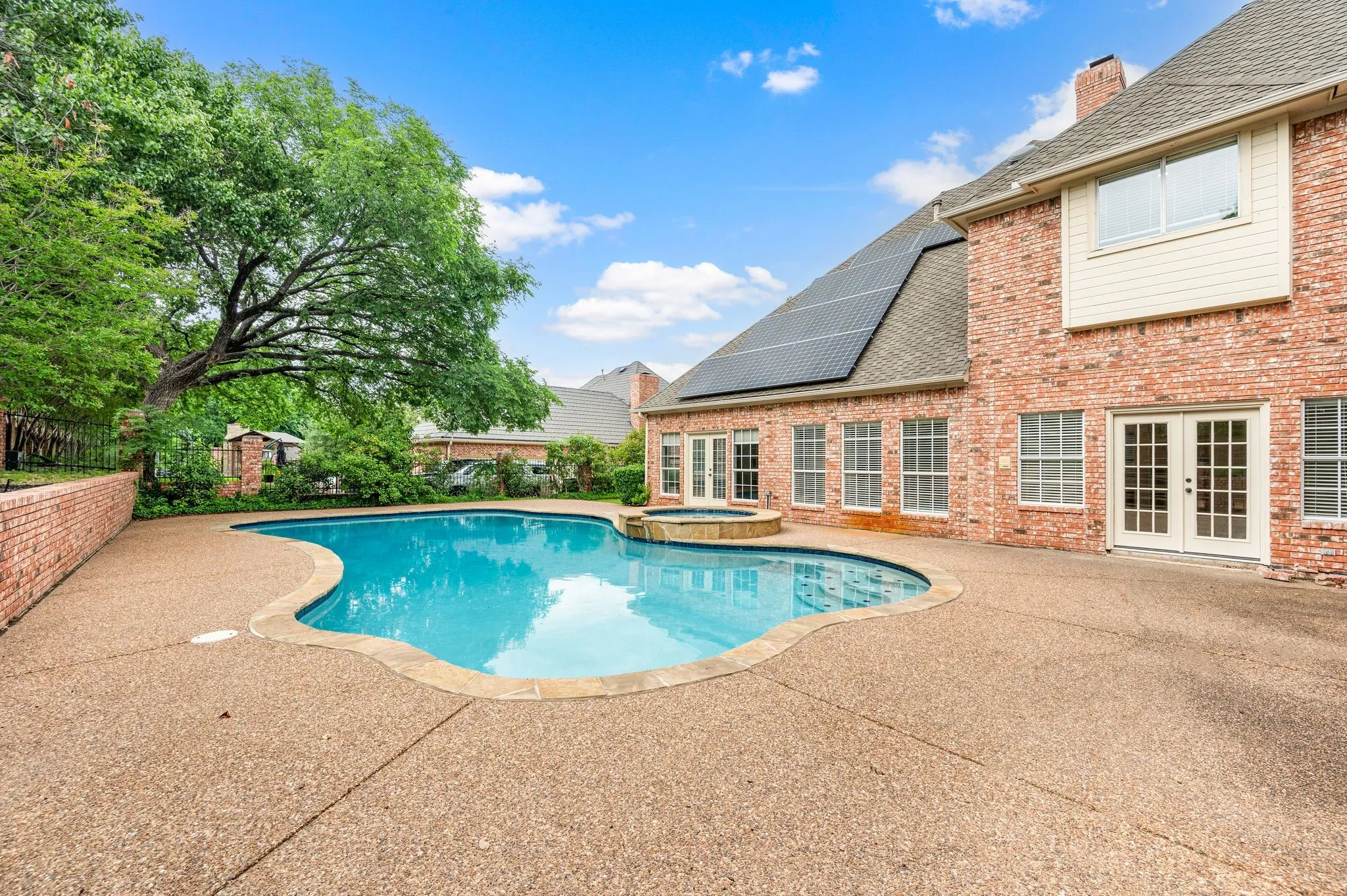 View of pool featuring a fenced backyard, a patio area, a pool with connected hot tub, and french doors