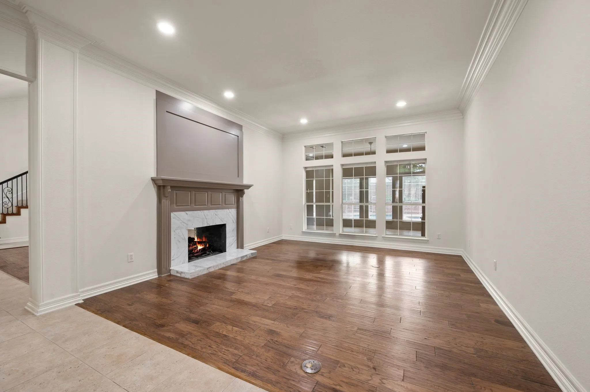 Unfurnished living room with crown molding, a premium fireplace, stairs, baseboards, and wood finished floors