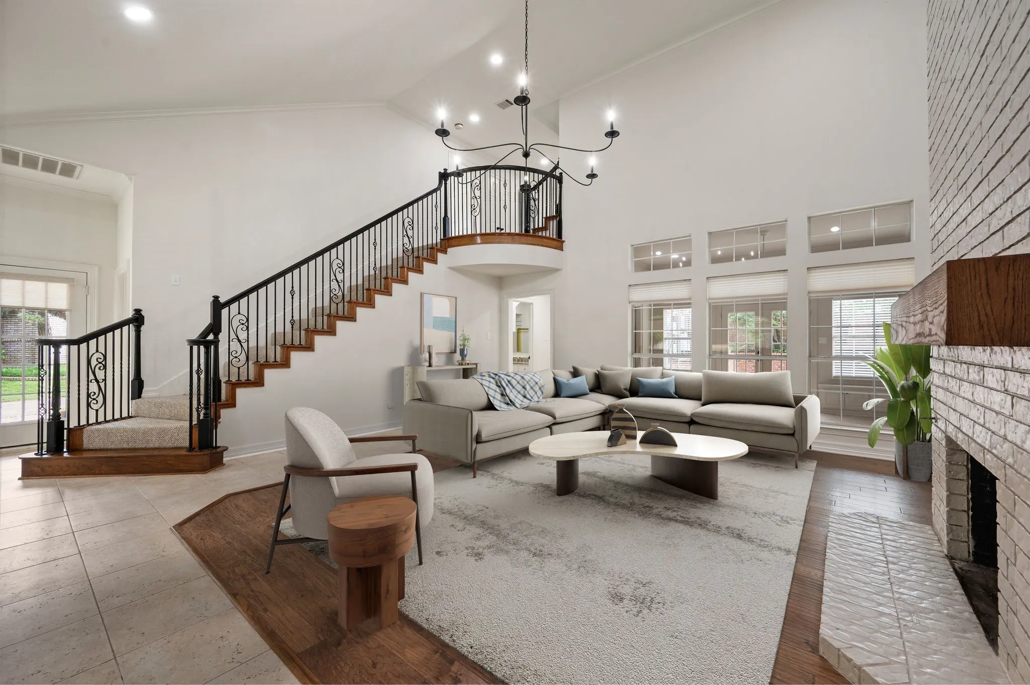 Living room featuring a brick fireplace, visible vents, stairway, and a towering ceiling