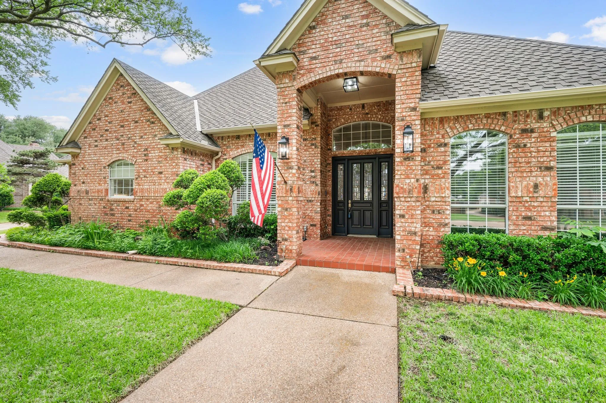 View of exterior entry with brick siding and roof with shingles
