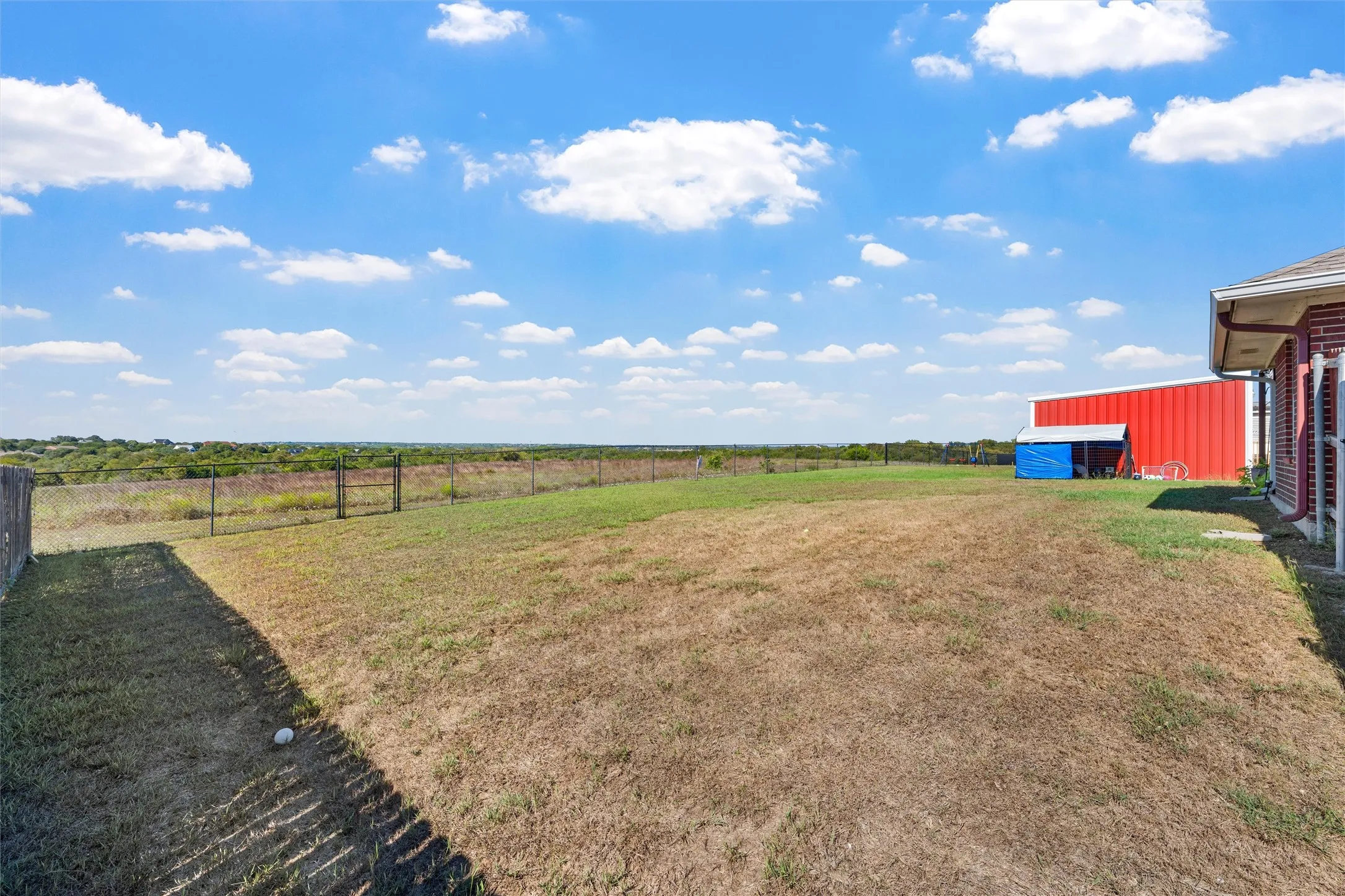 Expansive outdoor space featuring a perimeter fence and distant natural scenery