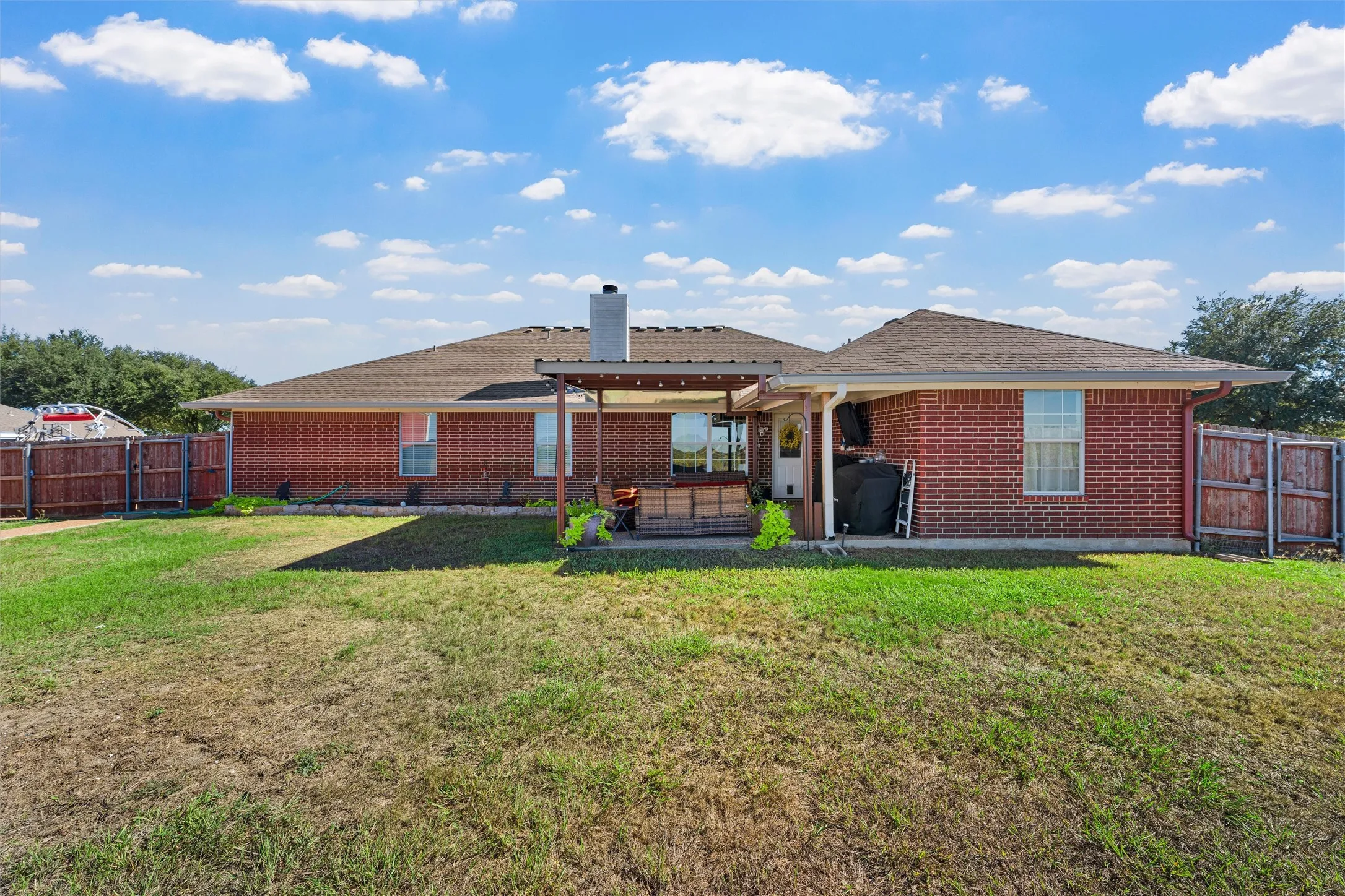 Brick exterior with a covered patio, fenced yard, and a single-story design