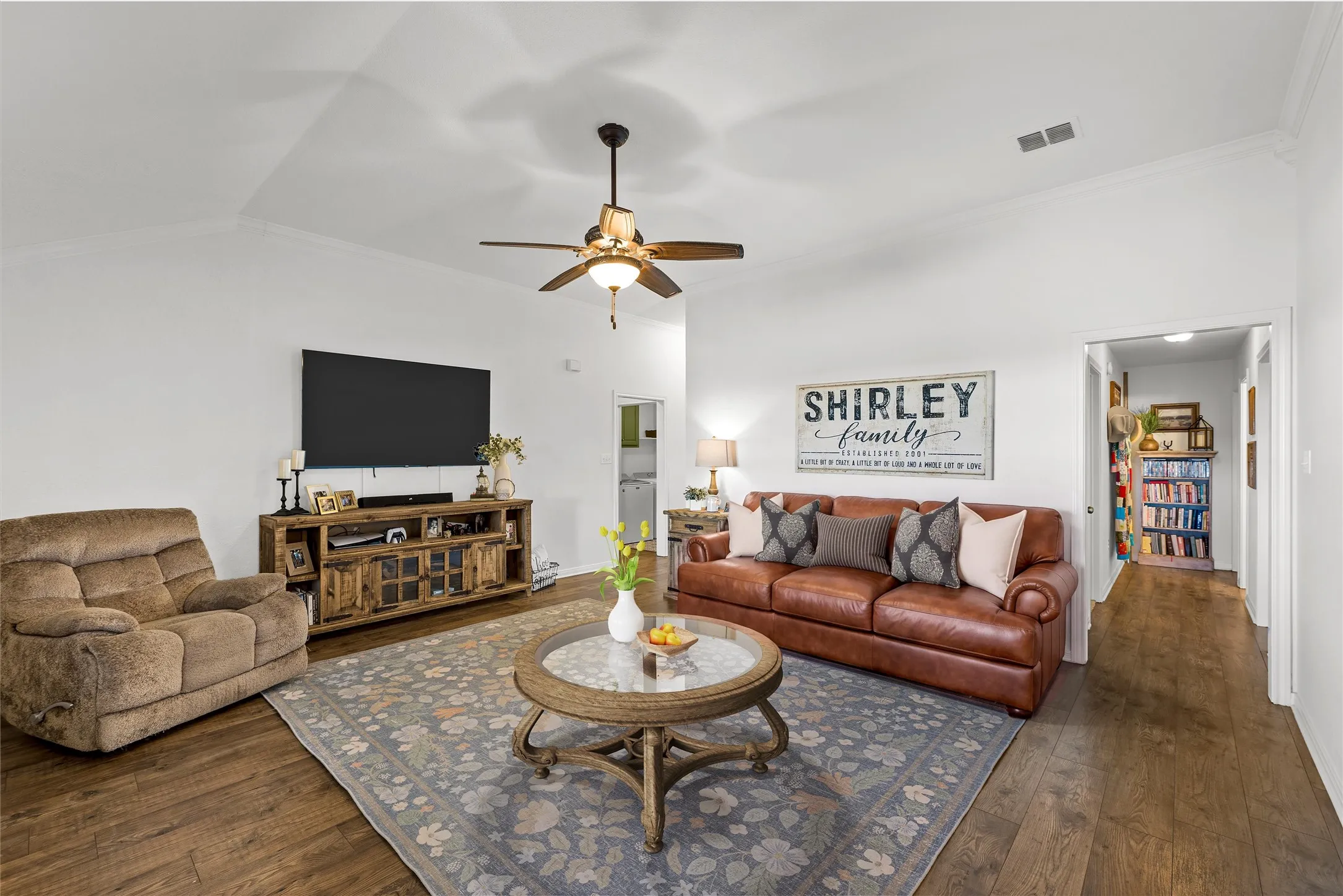Vaulted ceiling with crown molding, wood-finish flooring, and a ceiling fan with integrated lighting