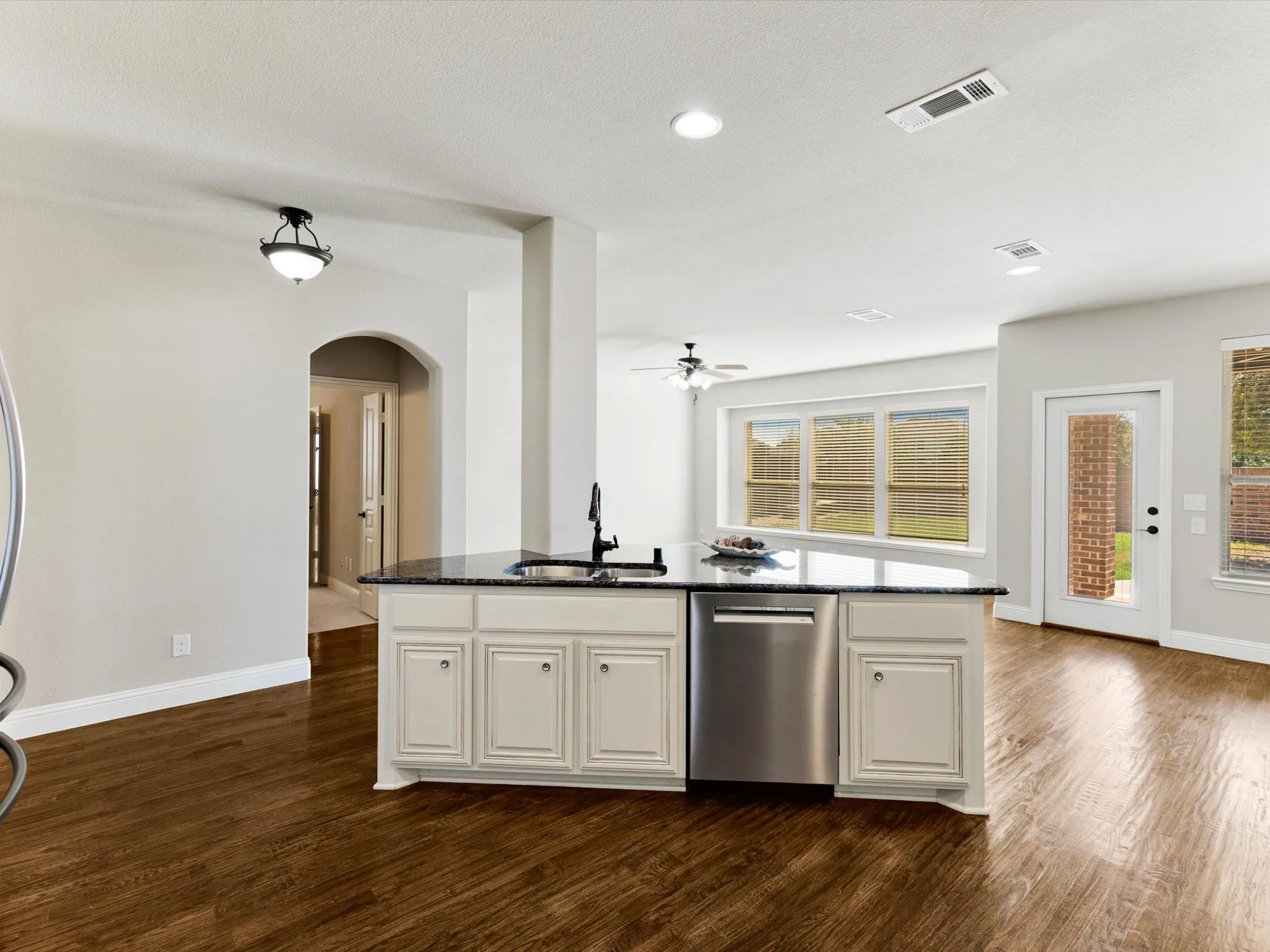 Kitchen island with a dark countertop, undermount sink, and stainless steel dishwasher