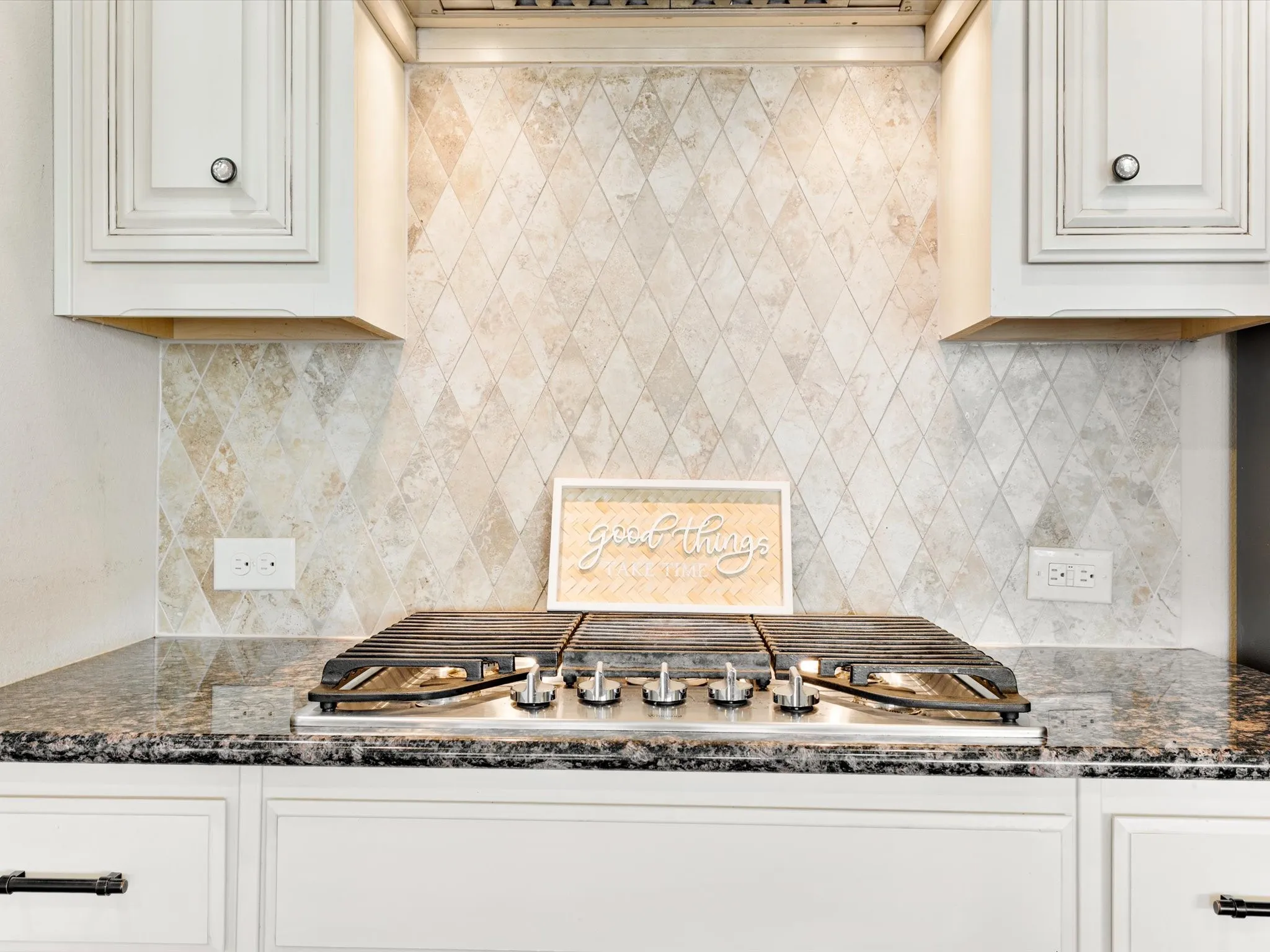 Built-in gas cooktop with polished metal accents, set within a speckled countertop