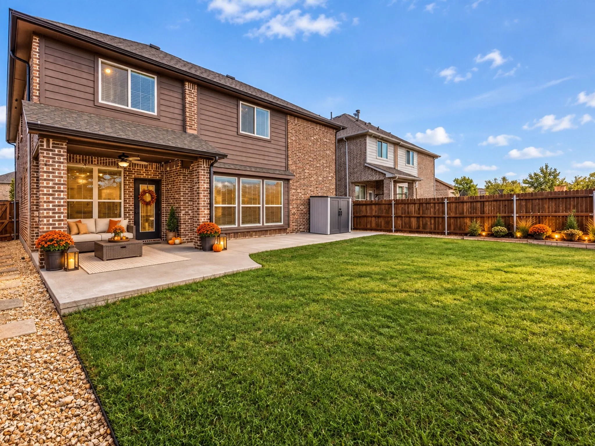 Expansive backyard featuring a manicured lawn, a large concrete patio, and a covered patio with an outdoor ceiling fan