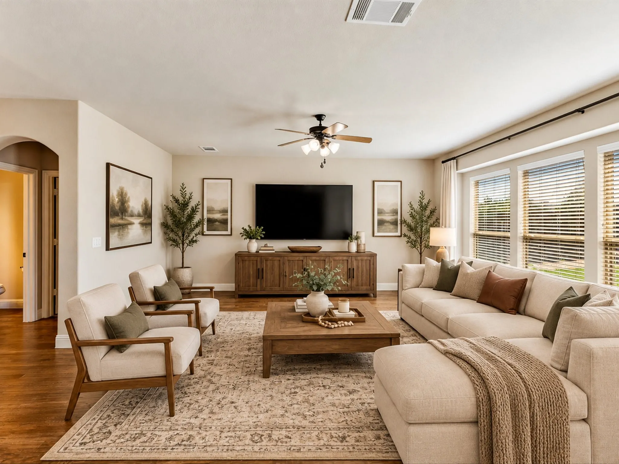 Expansive living space featuring wood-finish flooring, a ceiling fan, and multiple windows with blinds