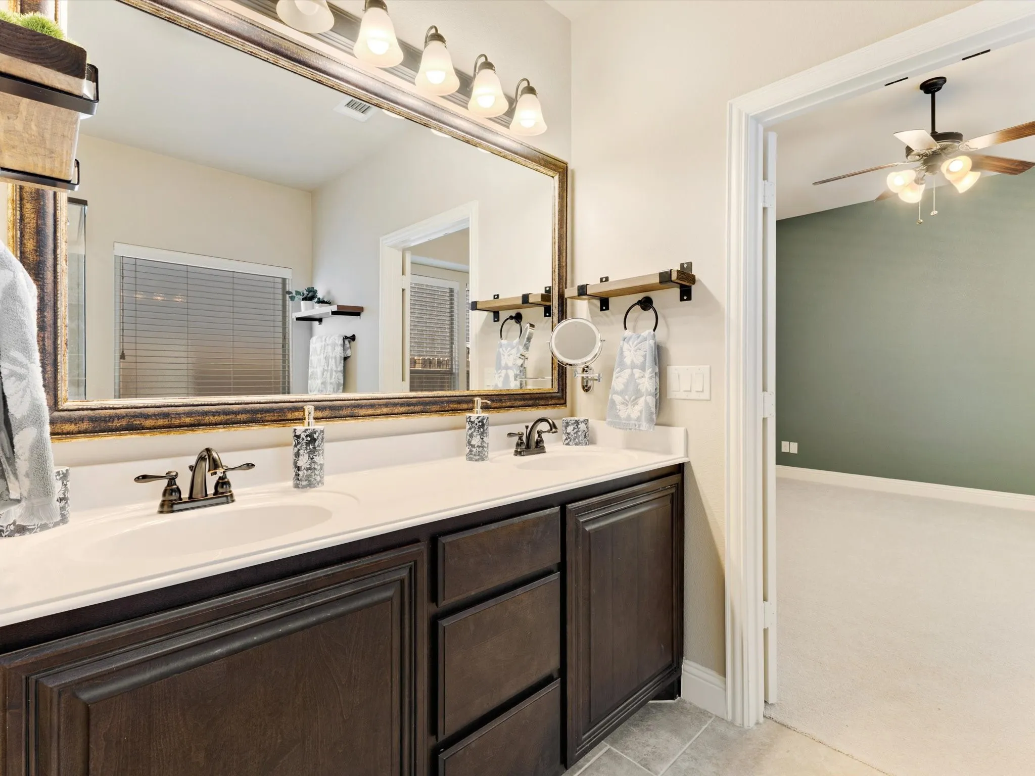 Dual vanity with dark wood-finish cabinetry, integrated sinks, and bronze-finish faucets