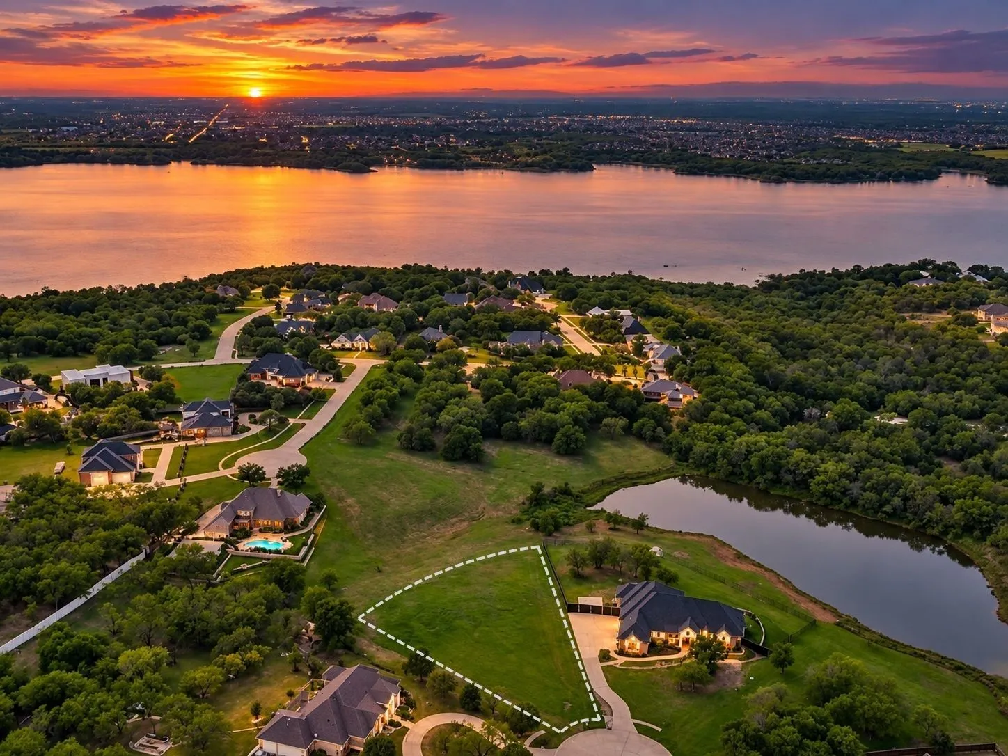 Expansive green lot featuring a water frontage, established residential surroundings, and direct road access