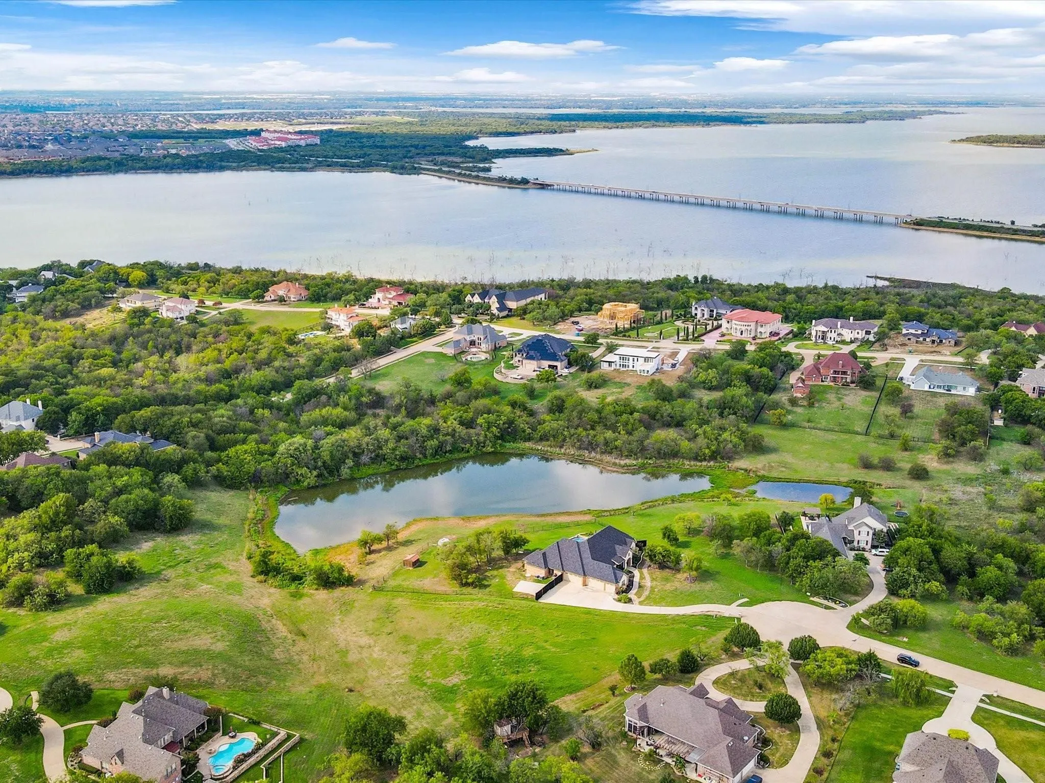 Expansive waterfront property featuring a private pond, lush green spaces, and a winding driveway