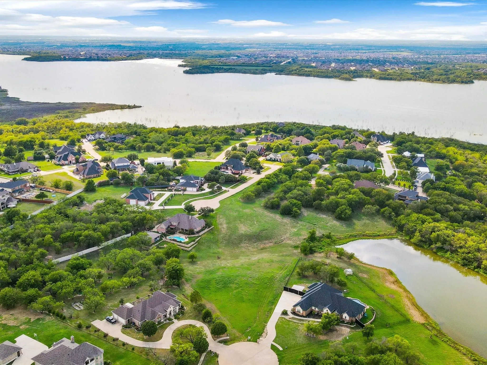 Residential development featuring a large body of water, extensive green spaces, and mature trees