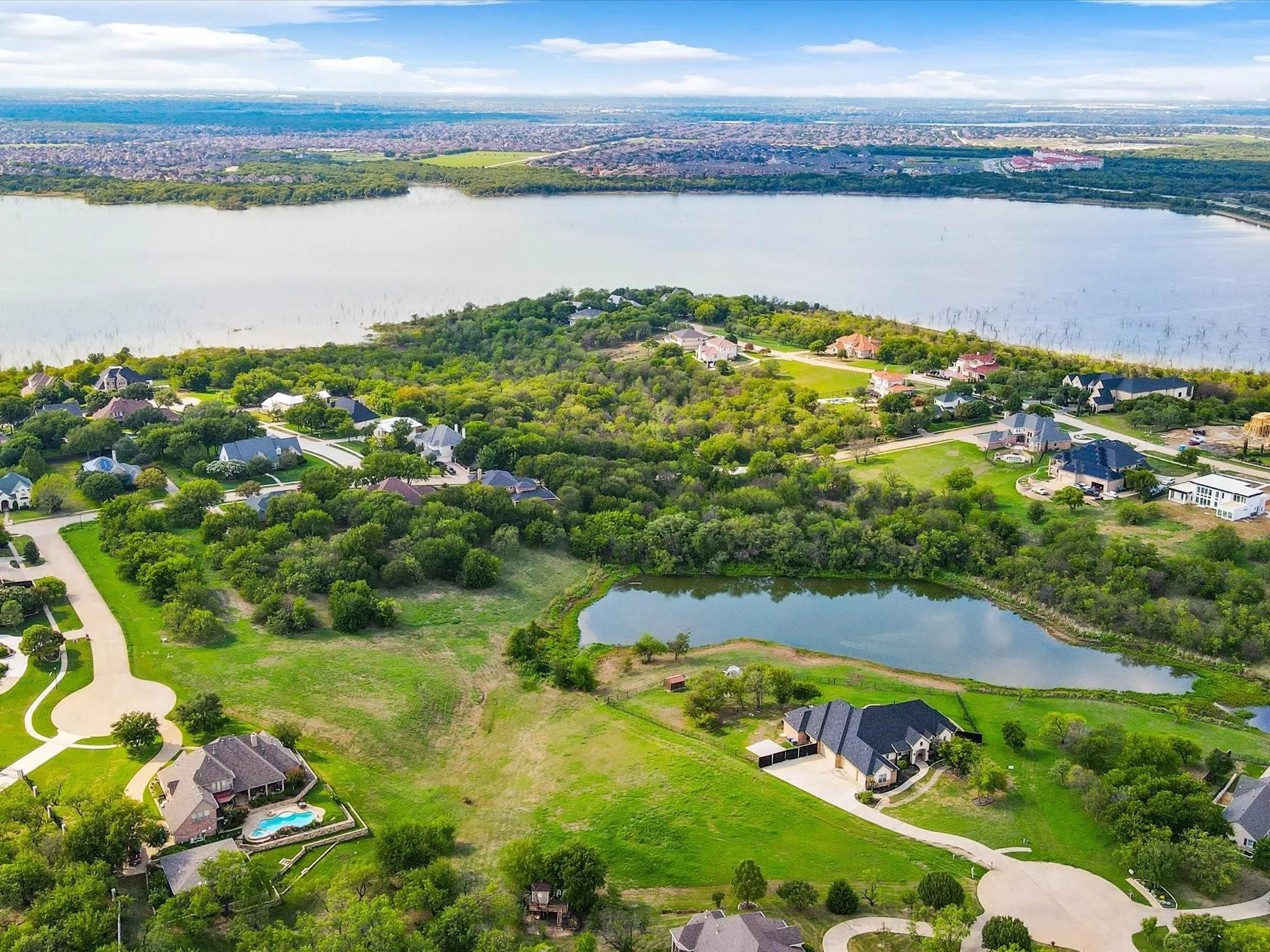 Expansive residential area featuring a large body of water, lush green landscaping, and multiple properties with private pools