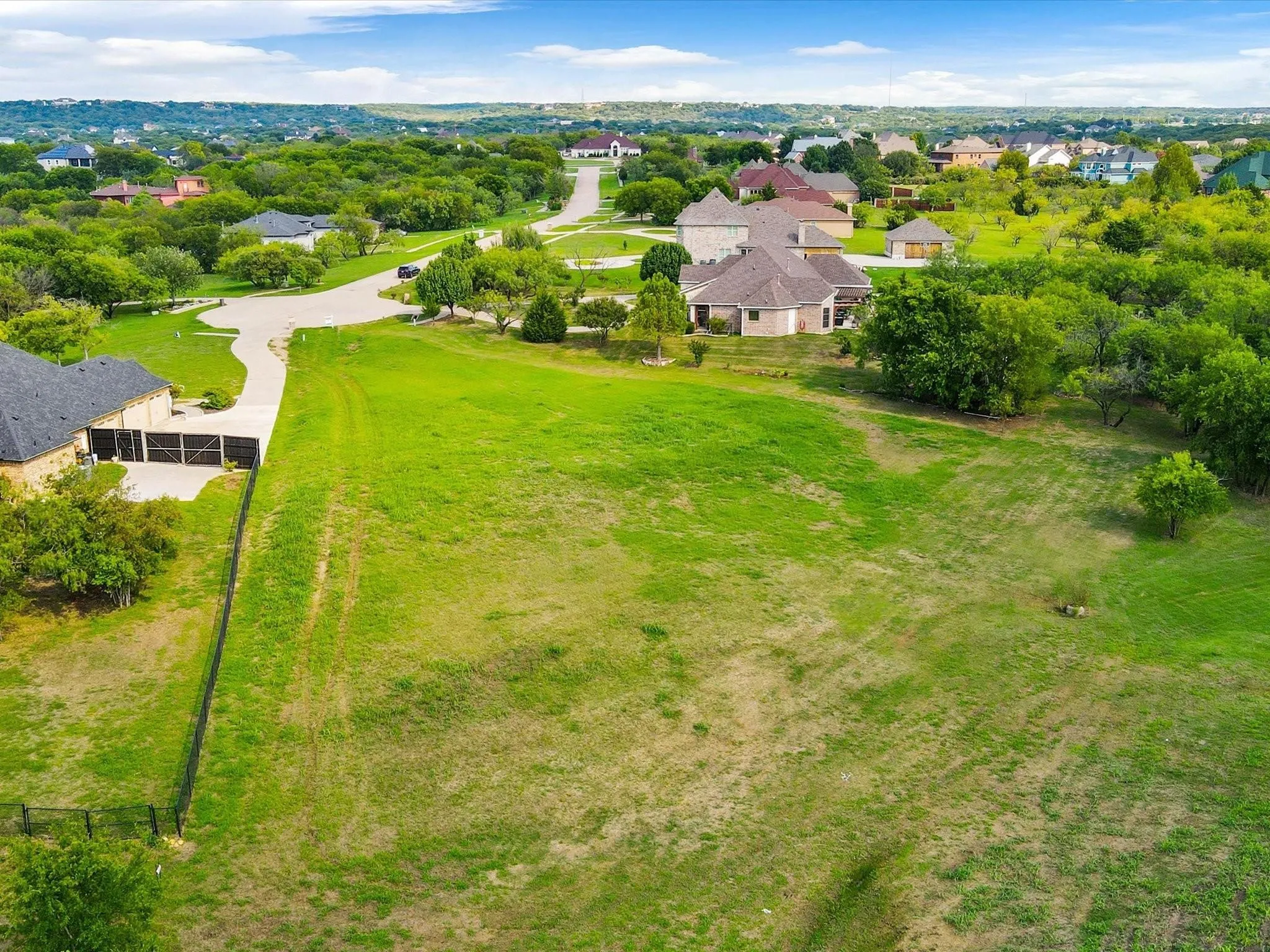 Expansive green lot featuring mature trees and a gently sloped terrain