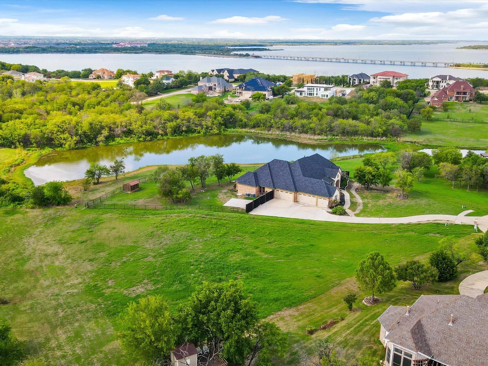 Expansive property featuring a private pond, extensive green space, and a waterfront backdrop