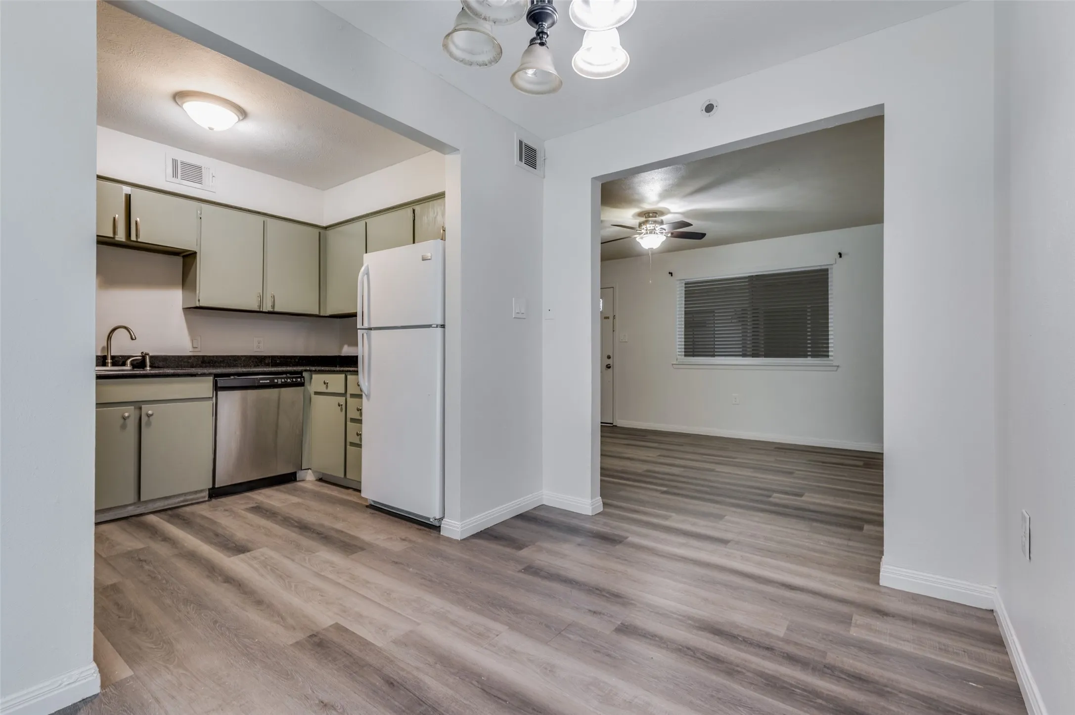 Kitchen with dark countertops, a stainless steel dishwasher, and a white refrigerator