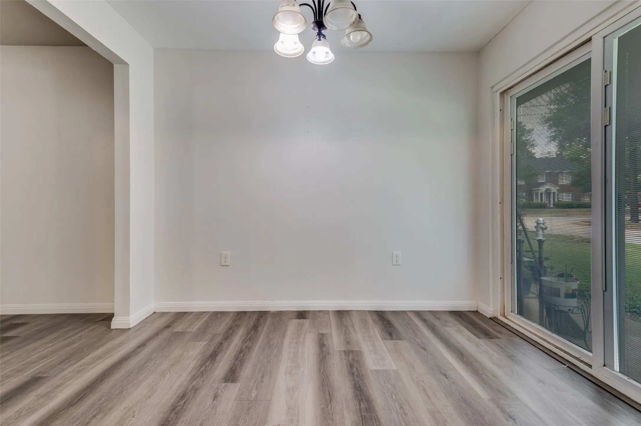 Wood-finish flooring, white walls, overhead ceiling light fixture, and sliding glass door