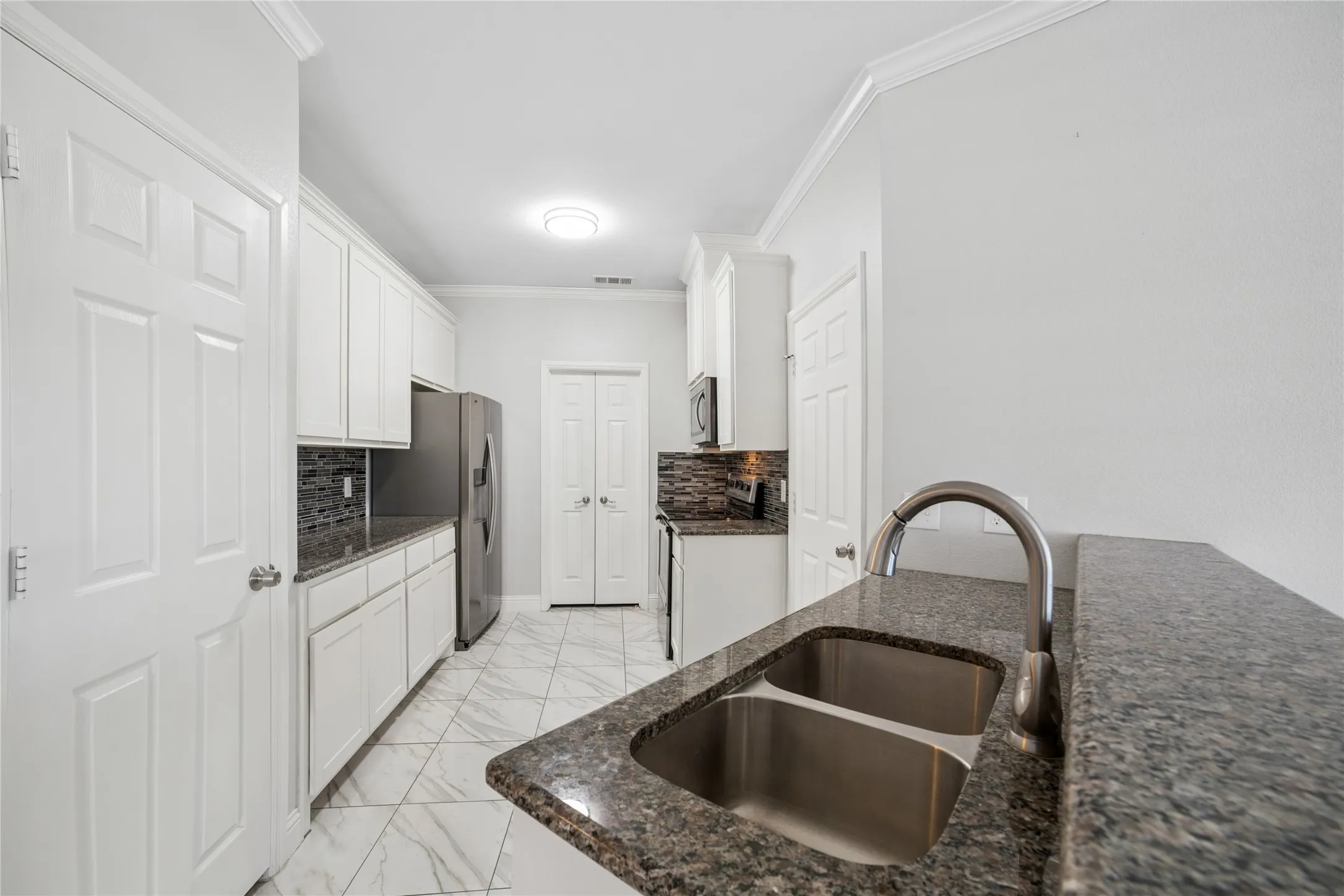 Kitchen featuring granite countertops, white cabinetry, a stainless steel double sink, and tile flooring