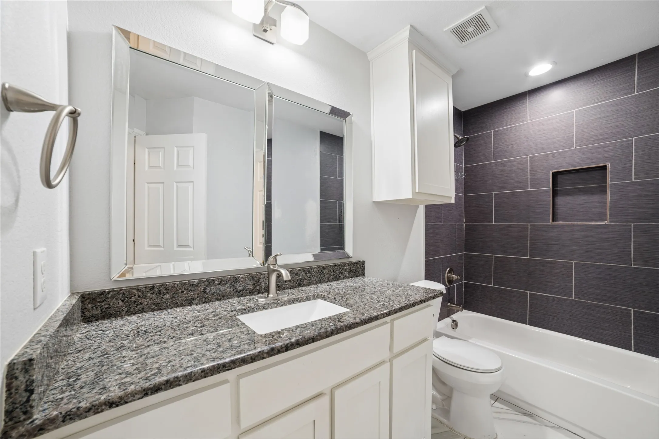 Vanity with a granite countertop, undermount sink, and brushed nickel faucet