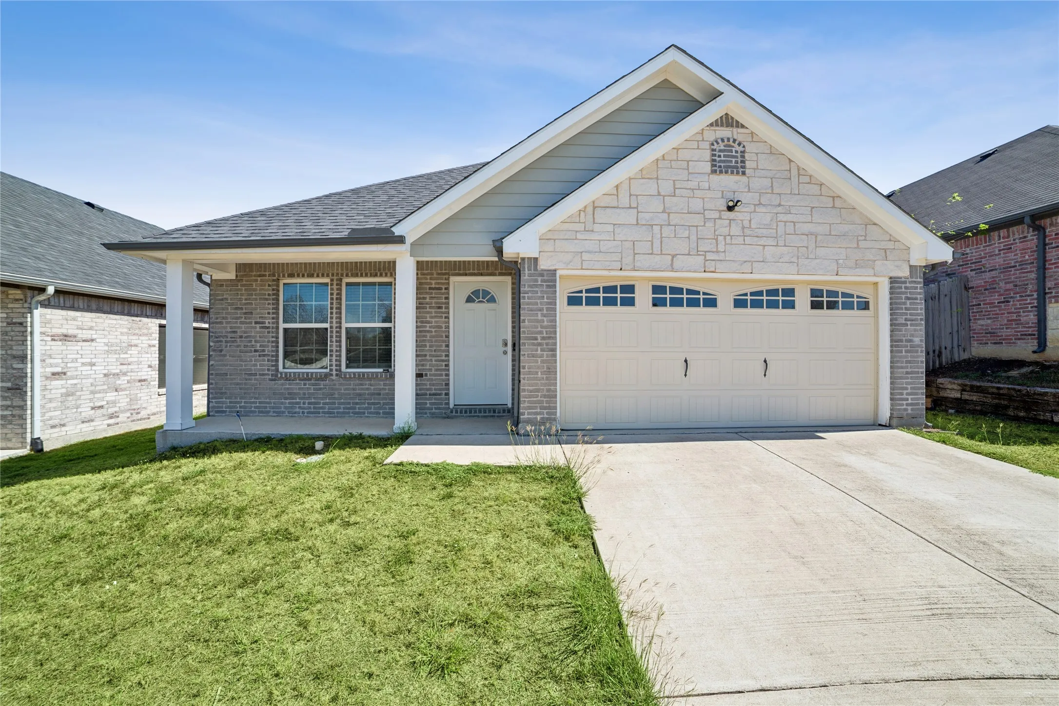 Stone facade and brick exterior with an attached two-car garage
