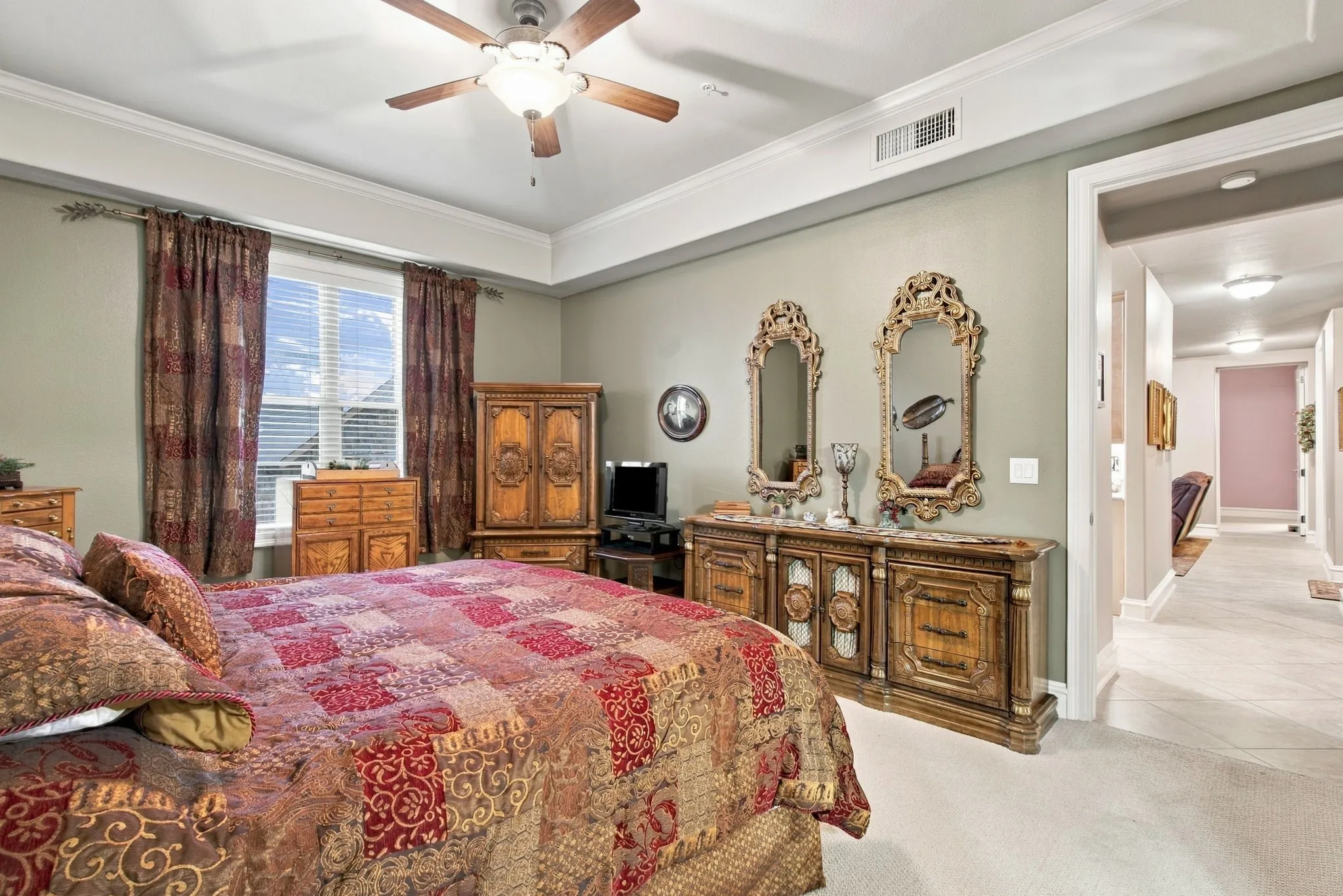 Recessed ceiling with crown molding, window with blinds, ceiling fan with integrated lighting, wall-to-wall carpeting