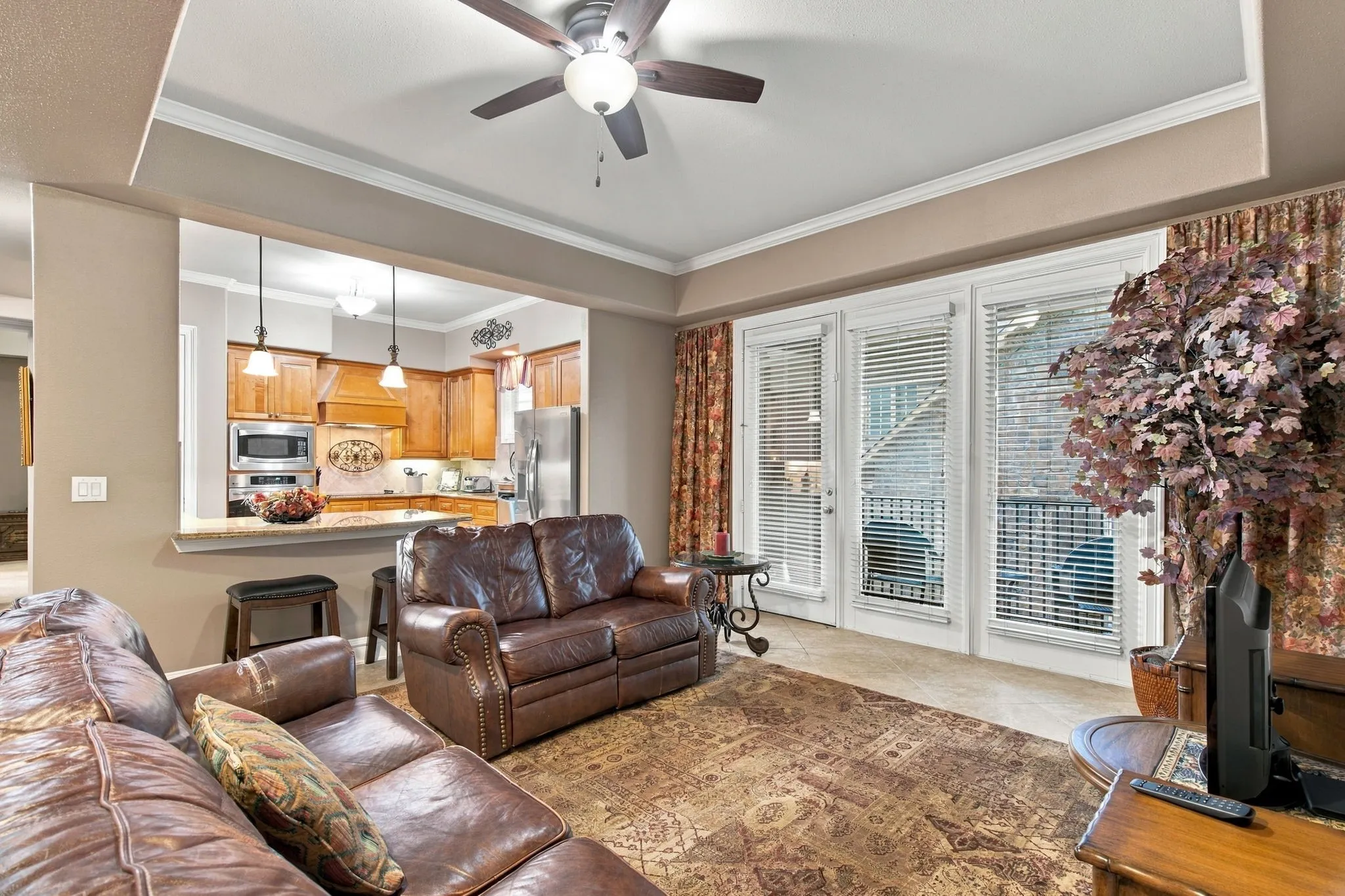 Living space featuring a ceiling fan, crown molding, and tiled flooring